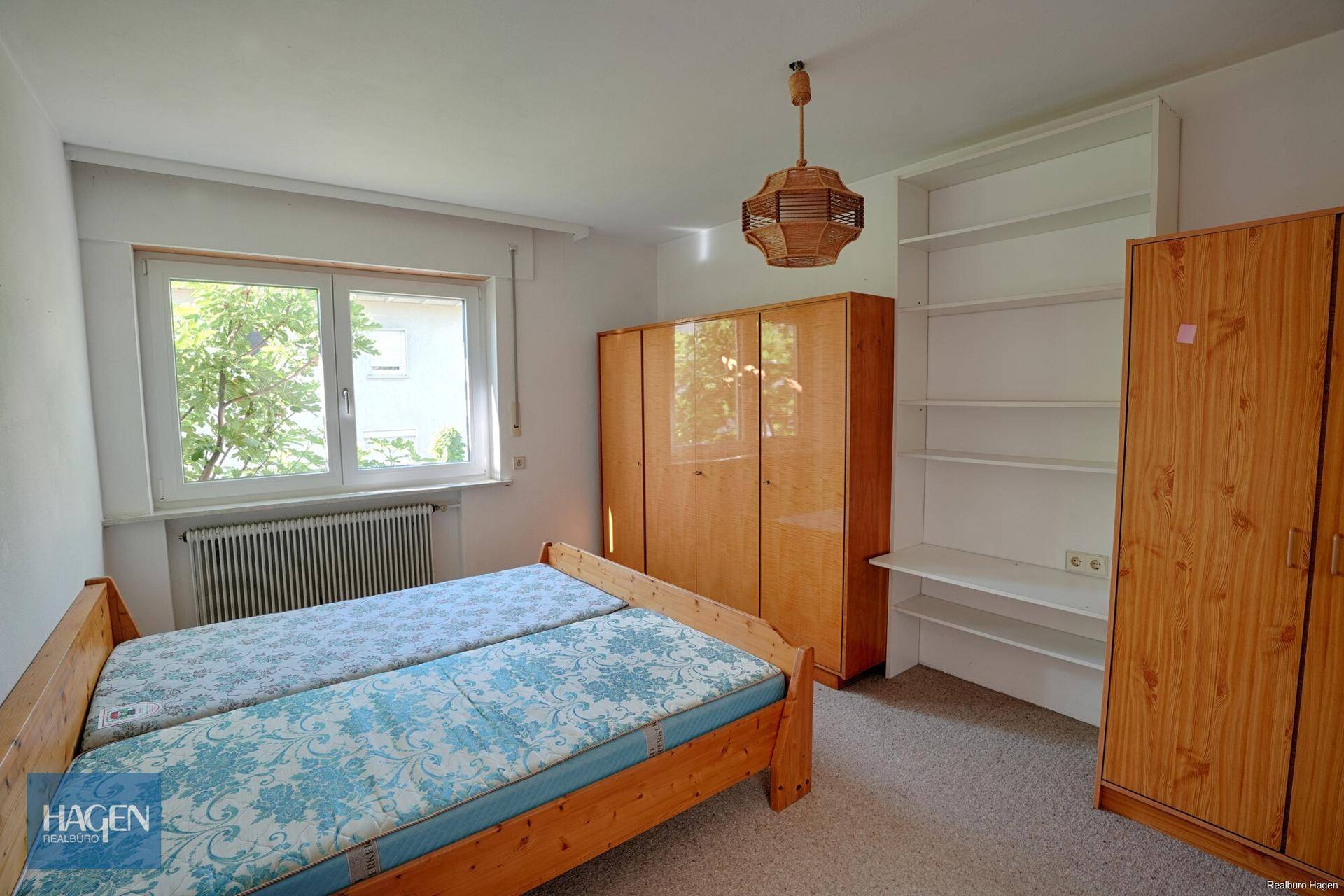 Schlafzimmer mit zwei Einzelbetten, Teppichboden und Holzschränken.