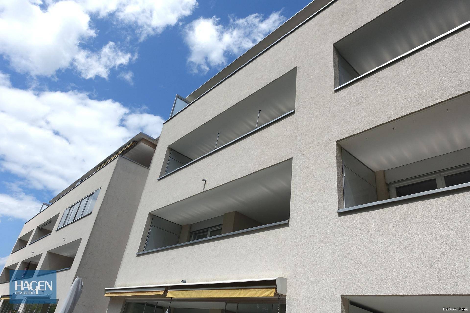 Moderne Gebäudefassade mit gestuften Balkonen und klarem Himmel im Hintergrund.