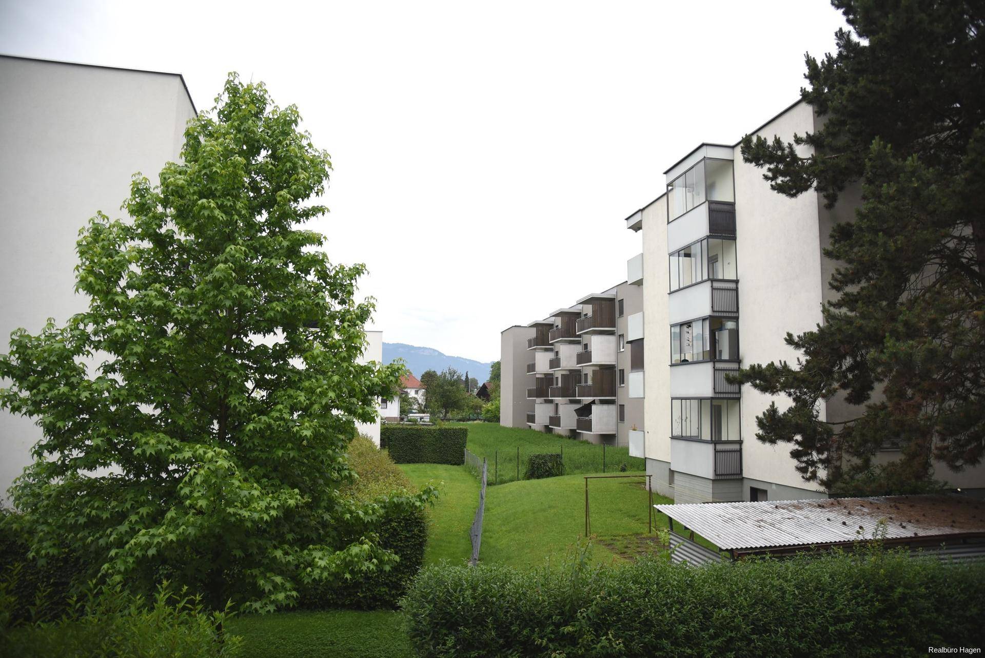 Wohngebäude mit gepflegten Grünflächen und Blick auf die umliegende Landschaft.