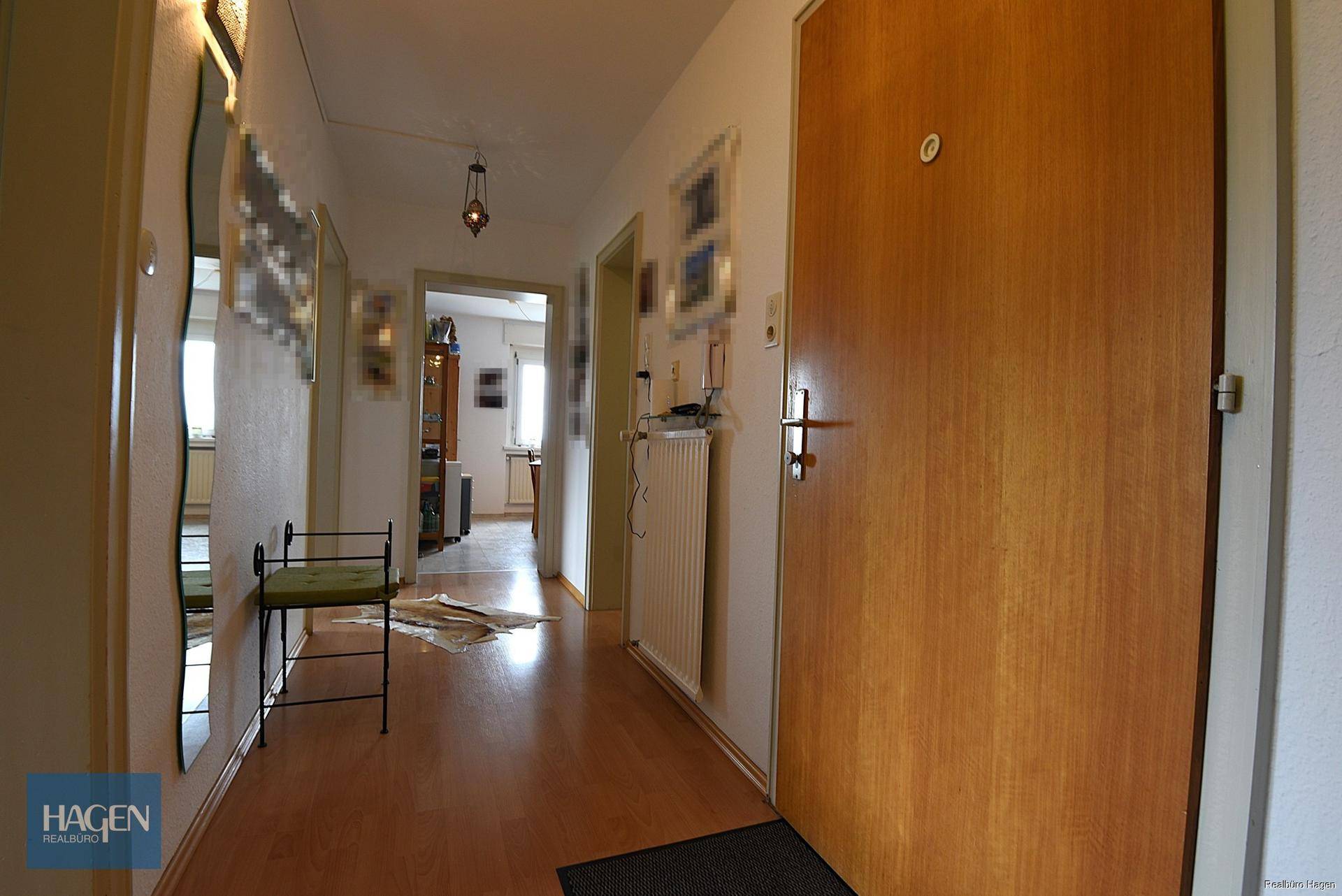 Heller Flur mit Holzfußboden und einer Holztür, die zu weiteren Räumen führt.