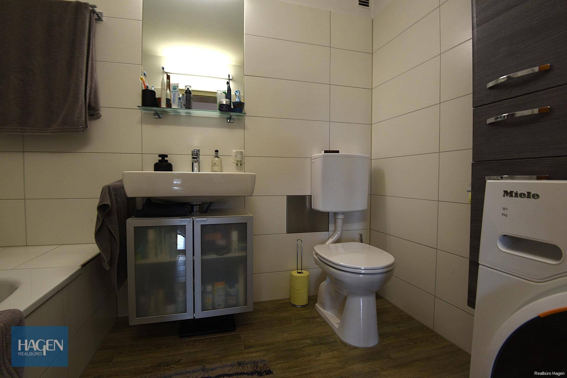 Modernes Badezimmer mit Waschbecken, Toilette, Badewanne und Waschmaschine.