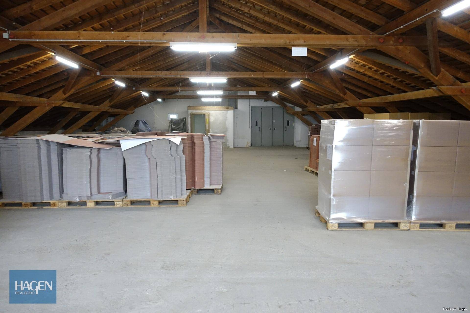 Geräumiger Dachboden als Lagerfläche mit sichtbaren Holzbalken und Paletten.