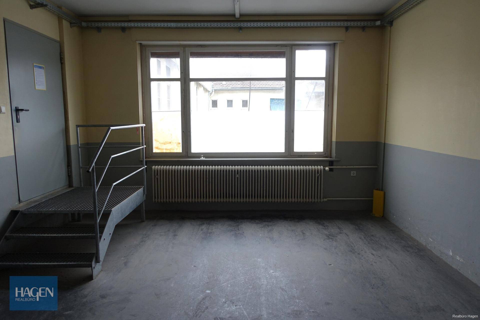 Kleiner Raum mit Fenster, Heizkörper und einer Metalltreppe.