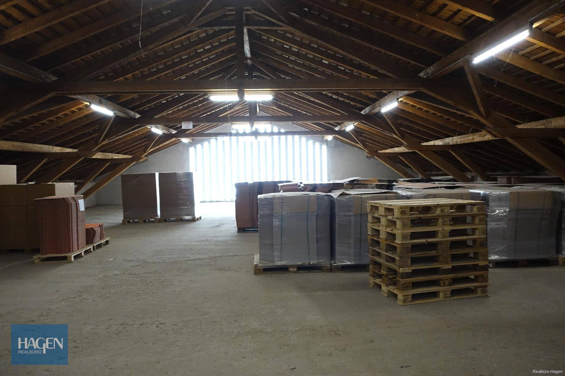 Großer Dachboden als Lagerfläche mit sichtbarer Holzkonstruktion und Paletten.
