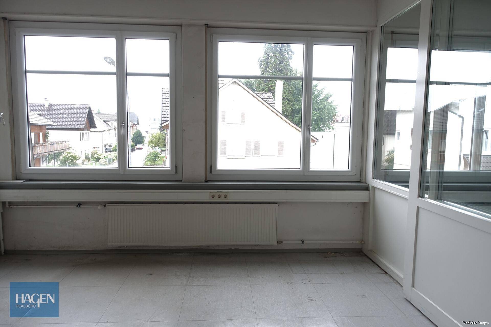 Große Fenster in einem Büroraum mit Blick auf die umliegenden Gebäude und die Straße.
