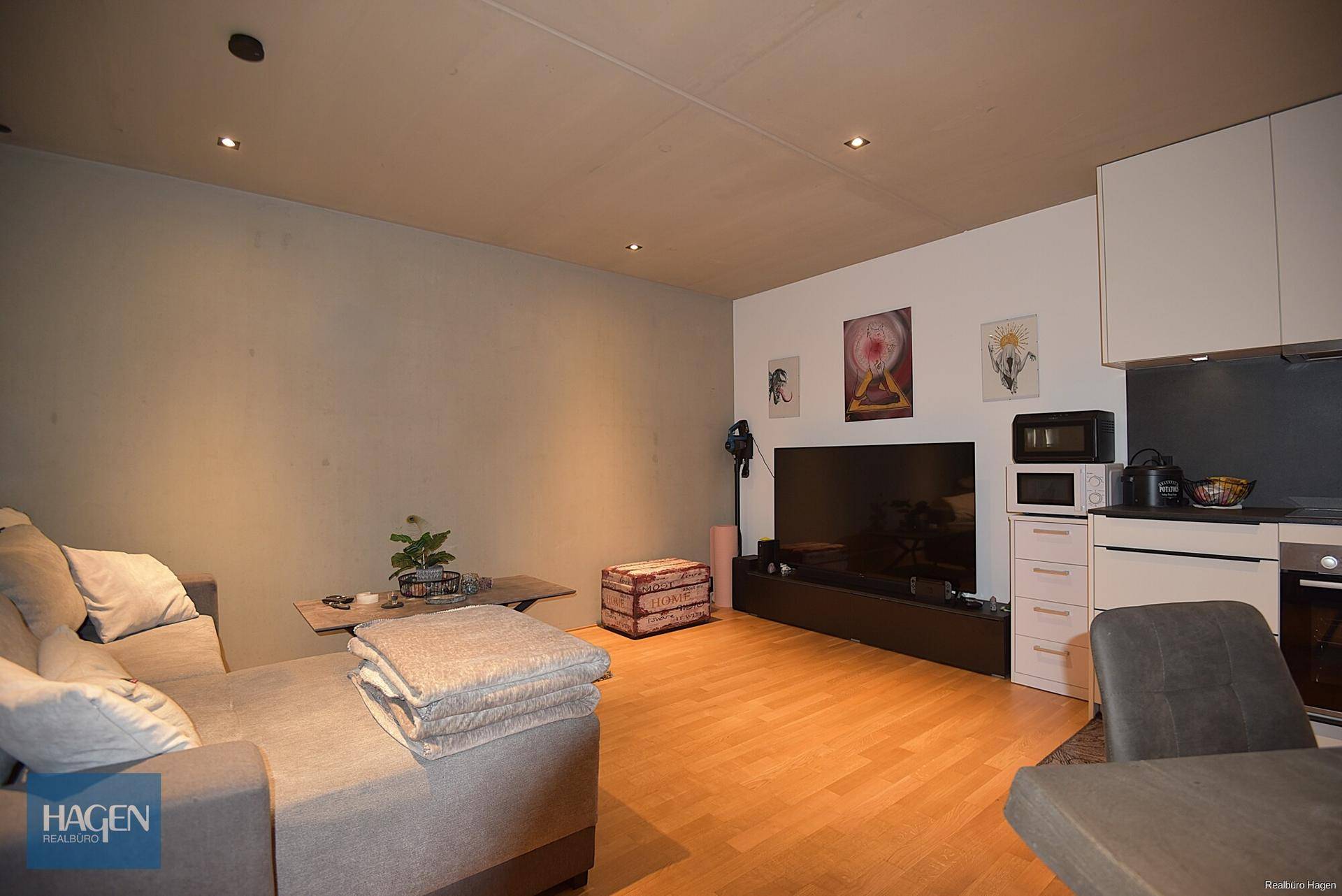 Gemütlicher Wohnbereich mit Sofa und großem Fernseher, Teil des offenen Wohnkonzepts.