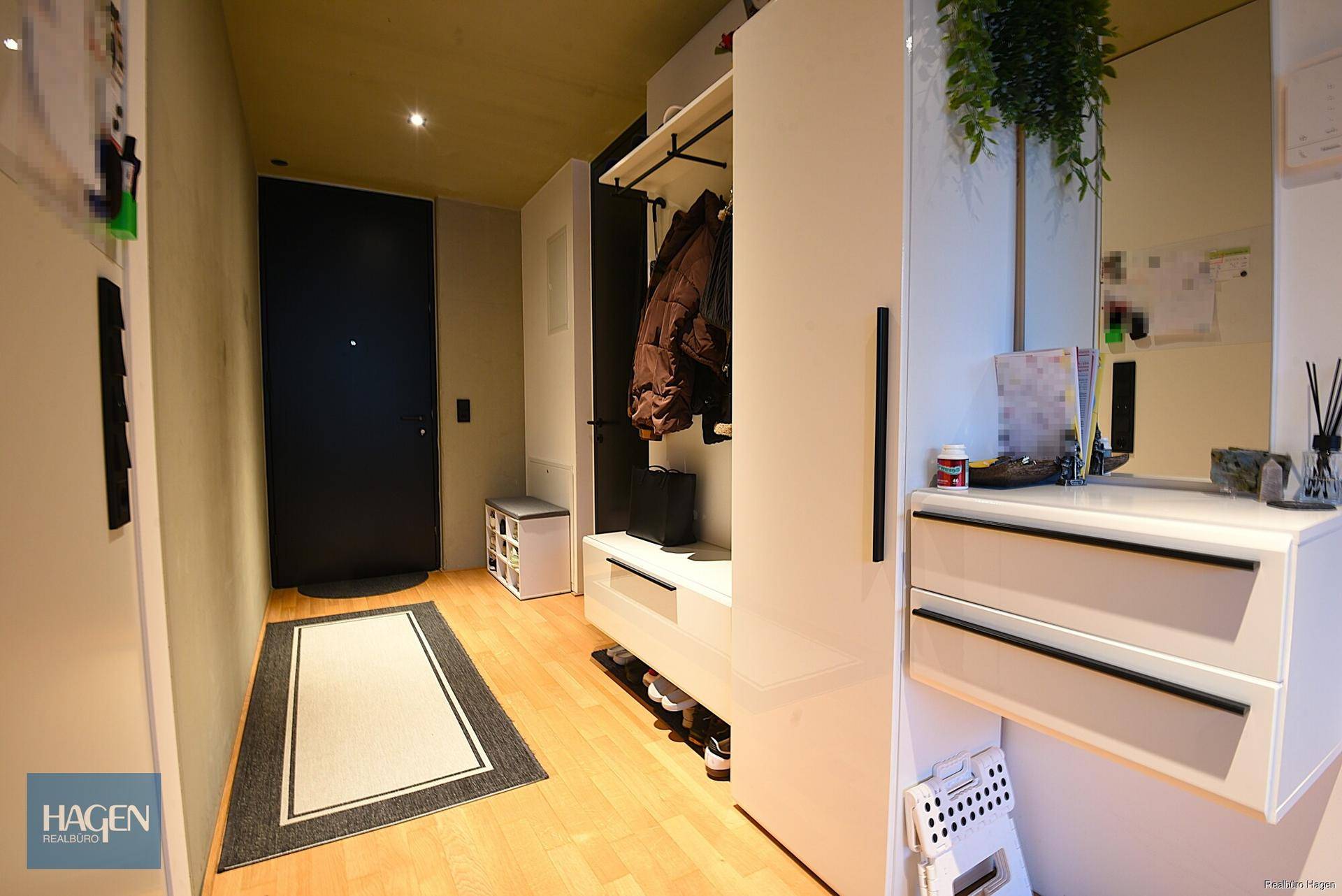 Heller Eingangsbereich mit integrierter Garderobe, Spiegel und Holzboden.