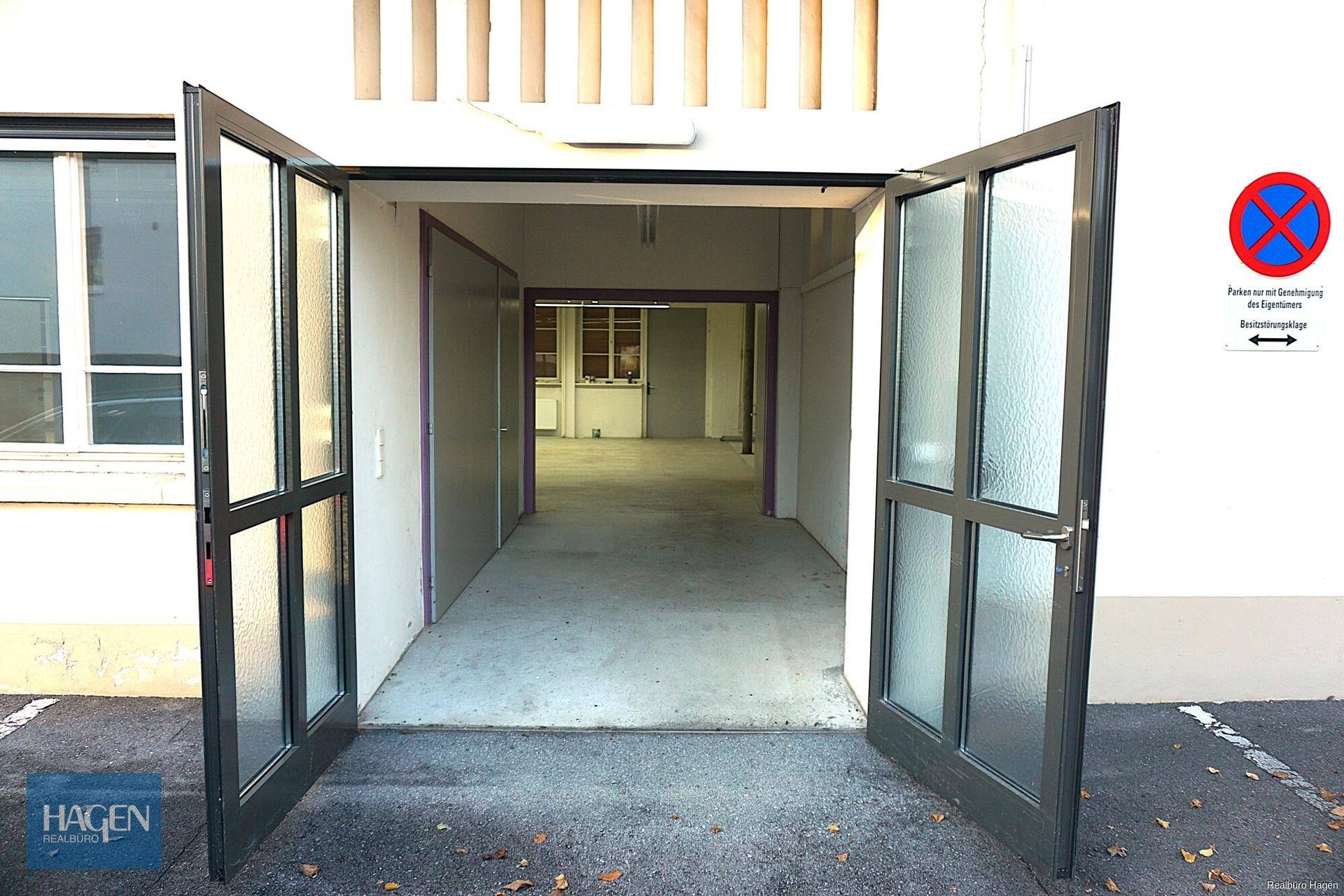 Offene Eingangstüren eines Geschäftsgebäudes, die in einen leeren Flur führen.