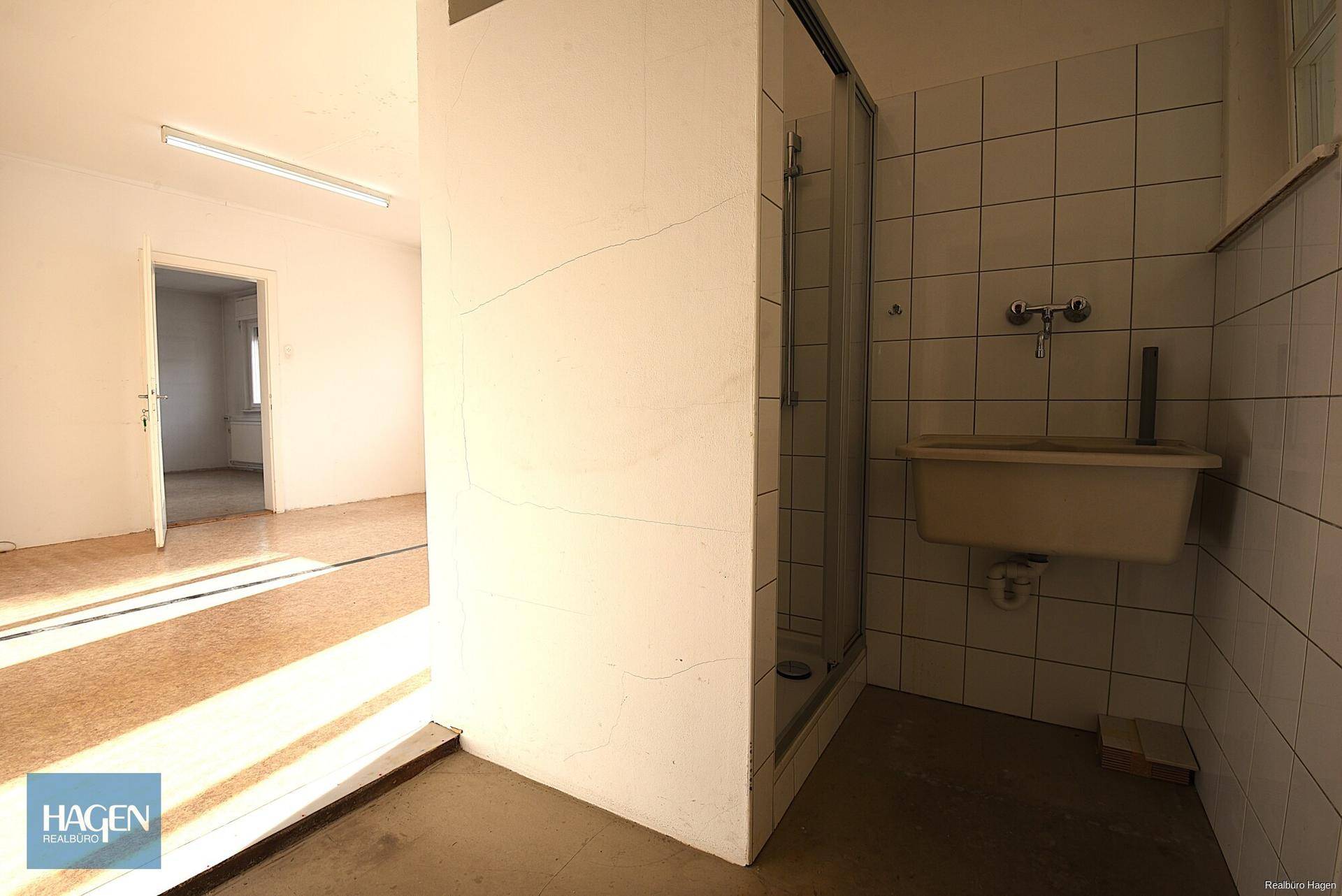 Einfaches Badezimmer mit Duschkabine, Waschbecken und gefliesten Wänden.