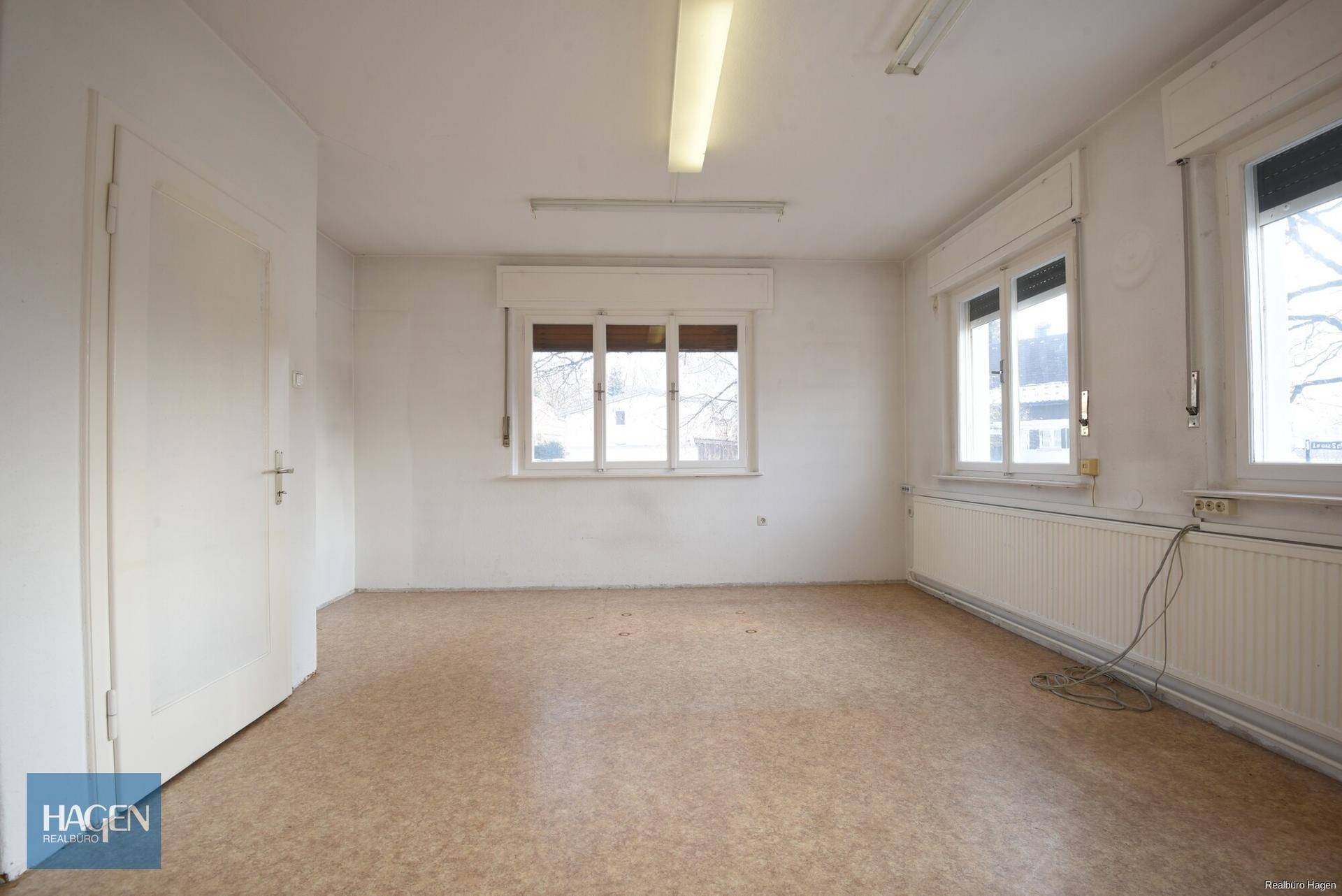 Geräumiger Büroraum mit mehreren Fenstern, Heizkörpern und Linoleumboden.