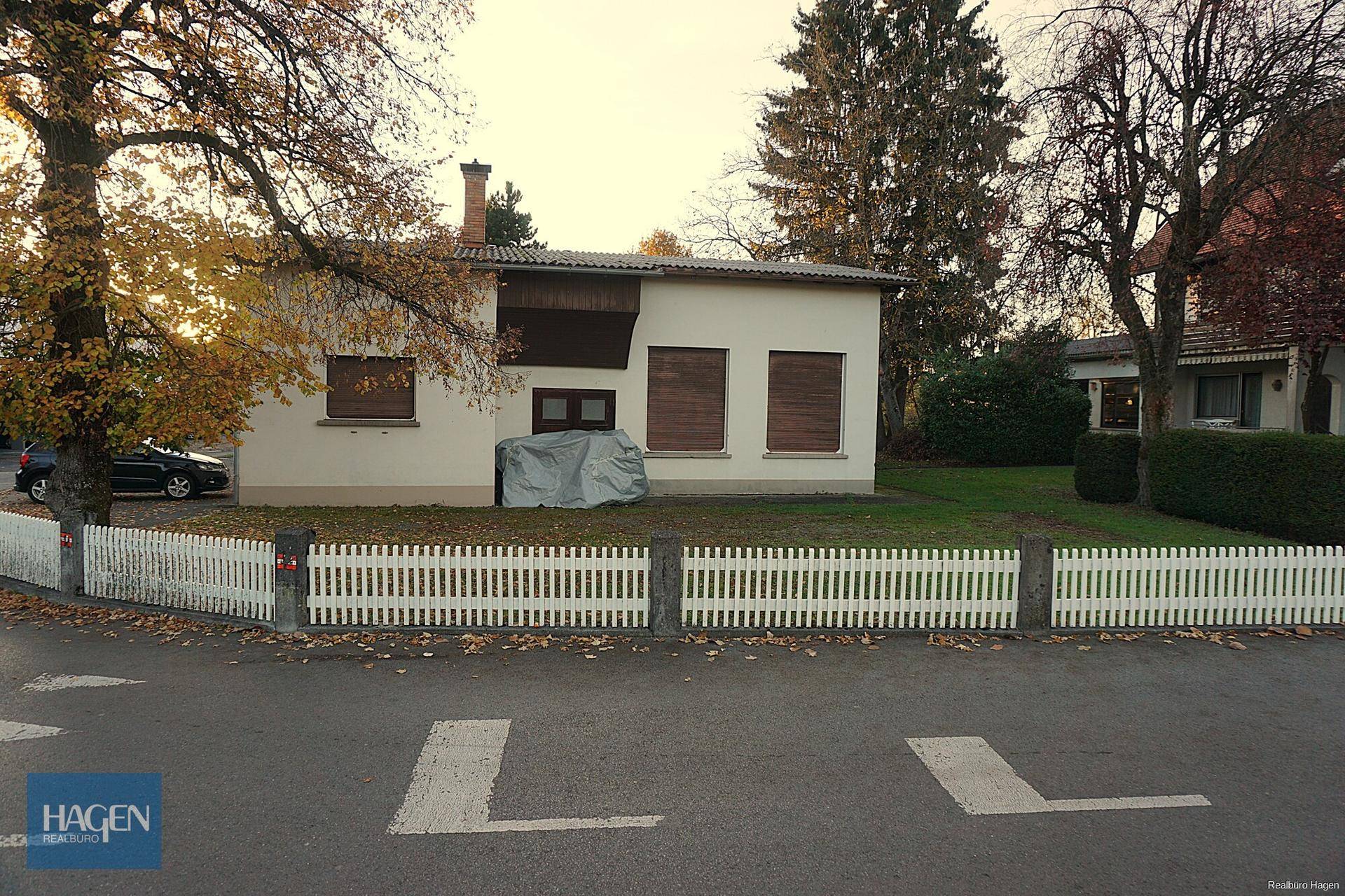 Rückansicht eines Gebäudes mit Gartenbereich und weißem Lattenzaun.