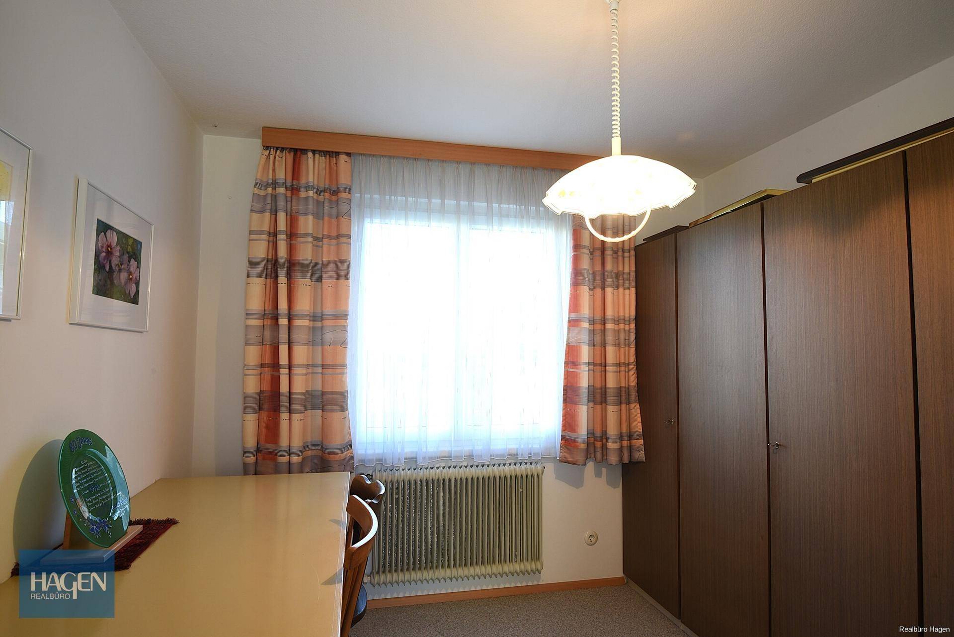 Einfaches Schlafzimmer oder Kinderzimmer mit großem Fenster und integriertem Kleiderschrank.