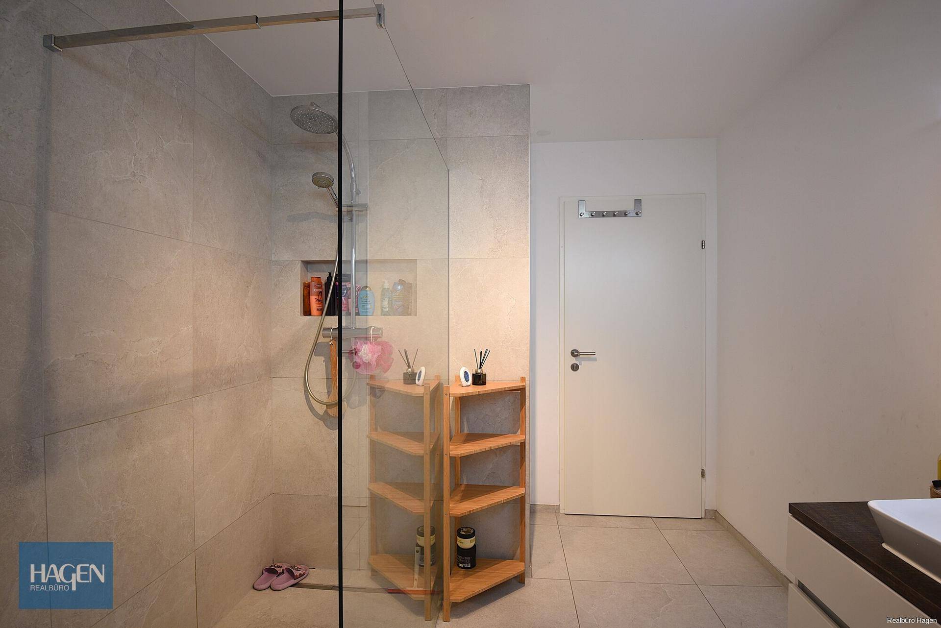 Geräumige begehbare Dusche mit Glaswand und modernen Fliesen im Badezimmer.