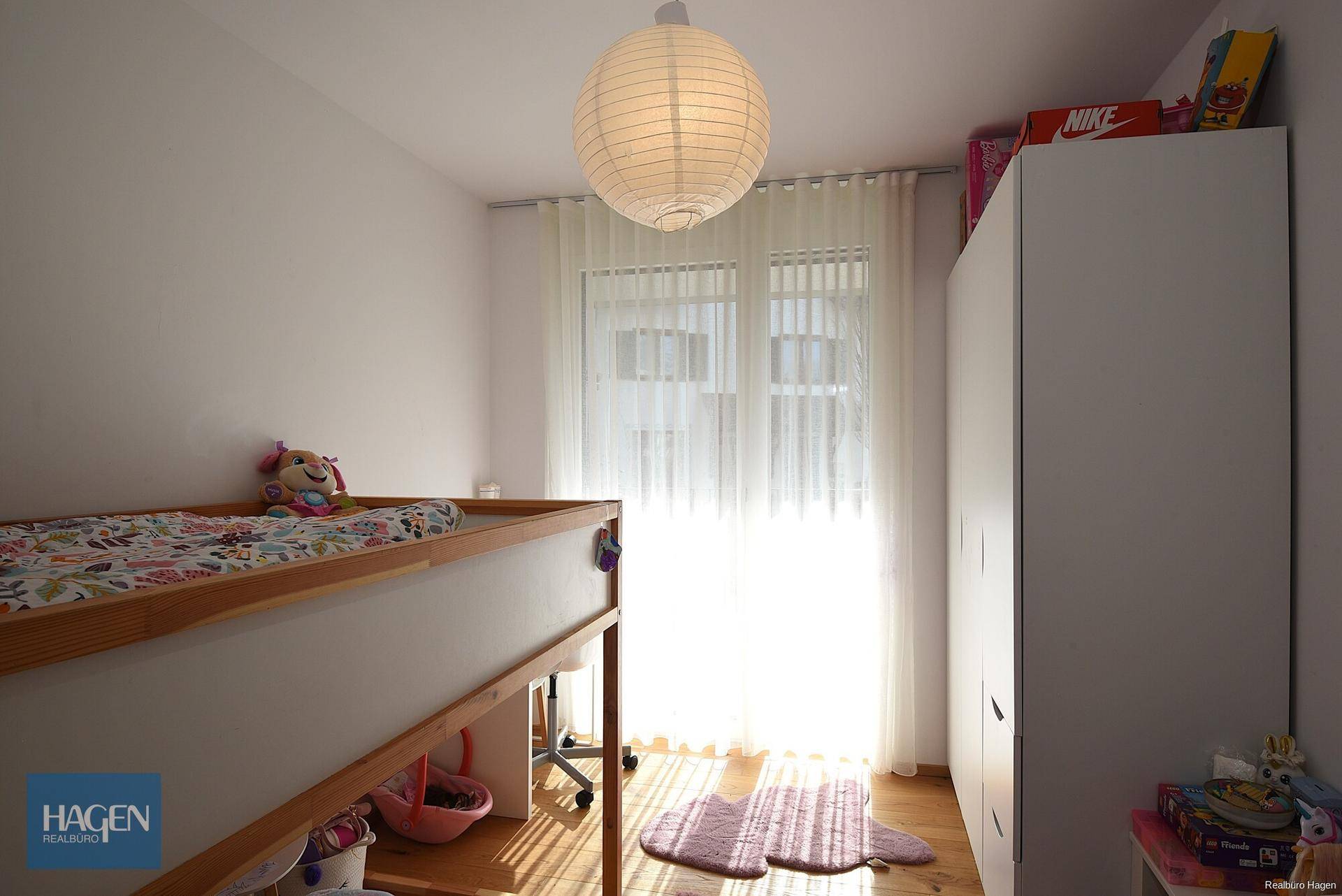 Kinderzimmer mit Hochbett, hellem Holzboden und großem Fenster für viel Tageslicht.