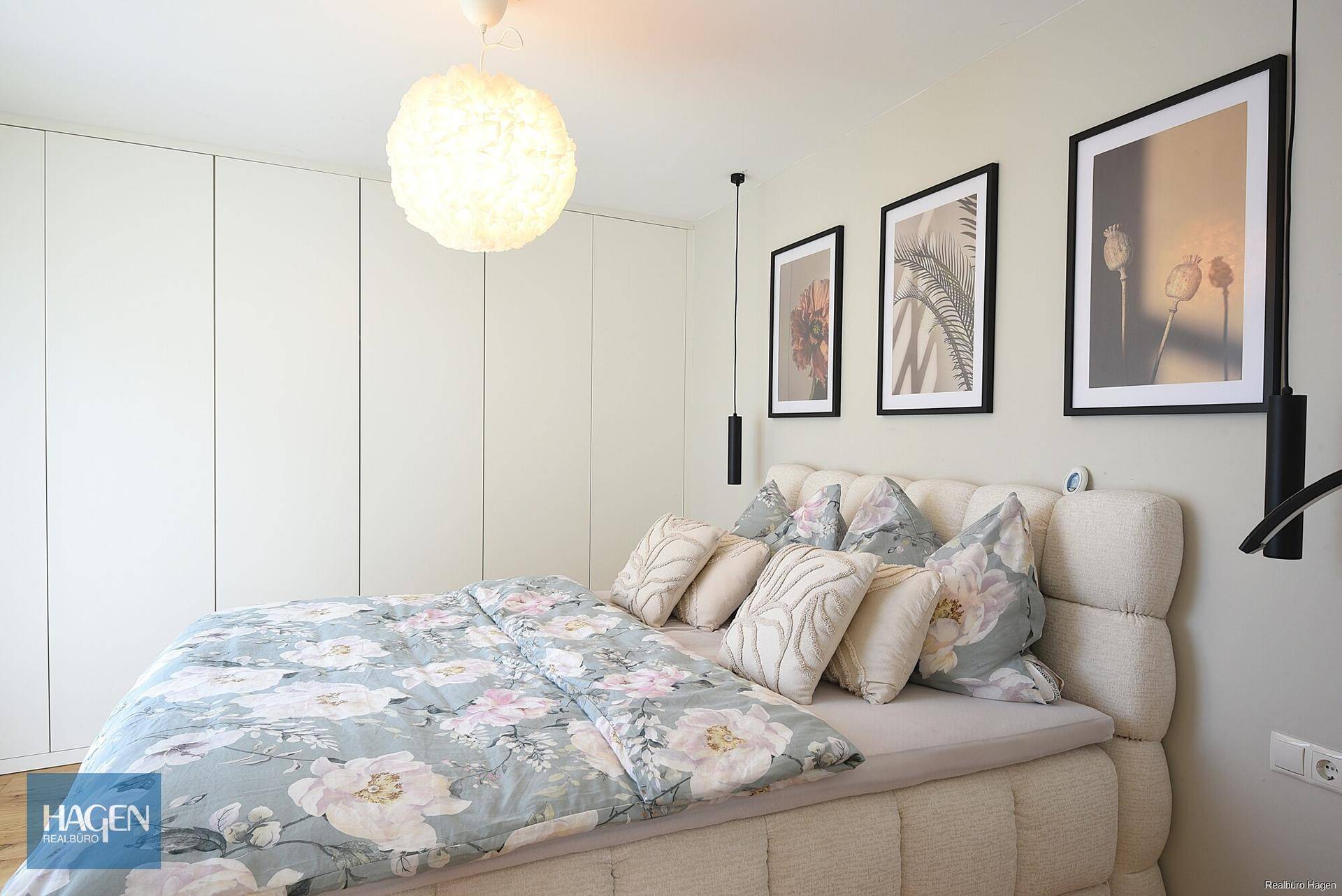 Helles Schlafzimmer mit großem Bett, floraler Bettwäsche und Einbauschränken.