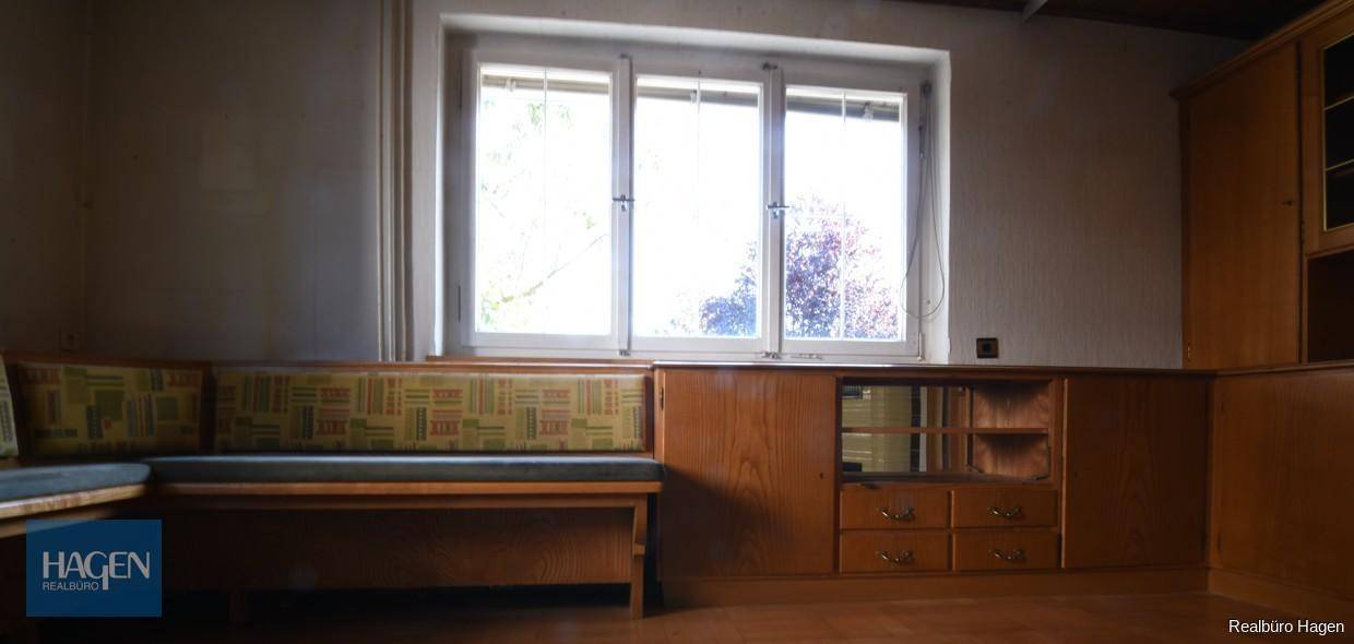 Gemütlicher Raum mit eingebauter Holzbank, Fenster und Holzvertäfelung.