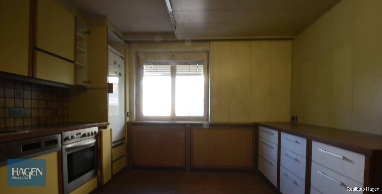 Ältere Küche mit gelben Schränken, Fliesen und Fenster, bereit zur Modernisierung.