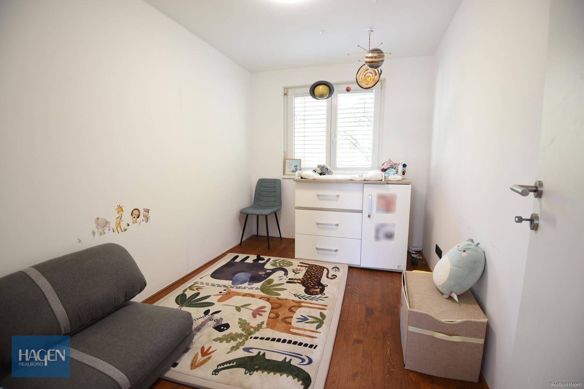 Kinderzimmer mit Holzboden, Fenster und bunter Dekoration, ideal für kleine Bewohner.
