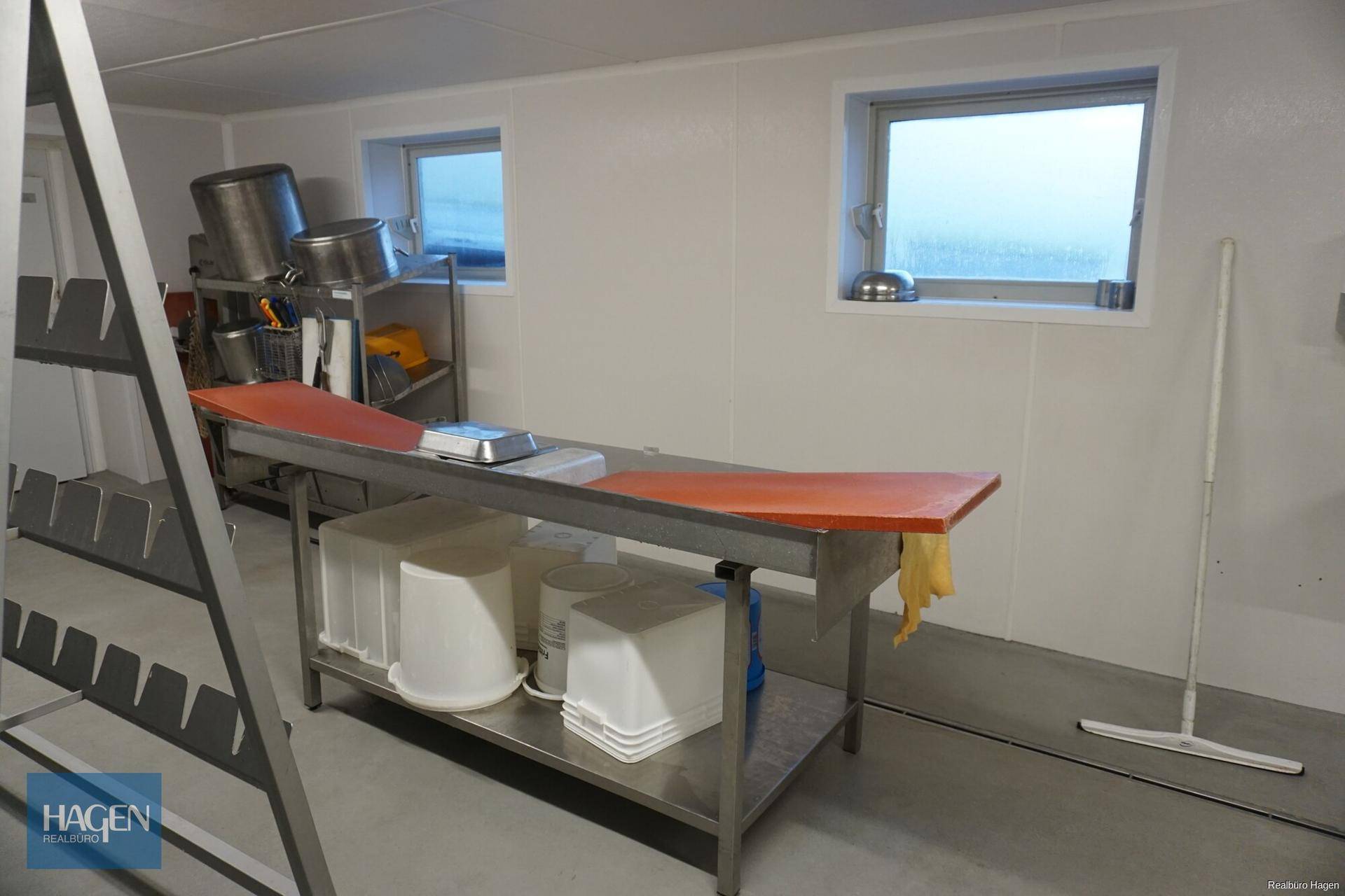 Weiterer Blick in den Verarbeitungsraum mit Edelstahltischen, weißen Eimern und Fenstern für Tageslicht.