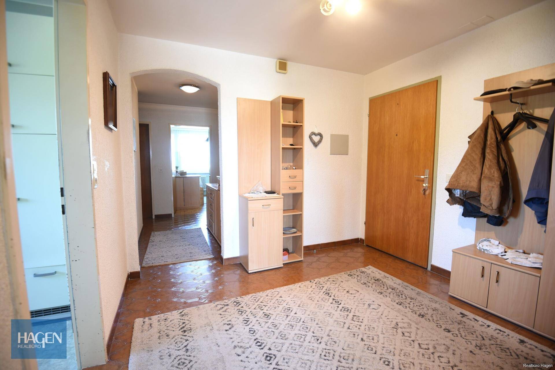 Heller Eingangsbereich mit Garderobe, Fliesenboden und Zugang zu weiteren Räumen.