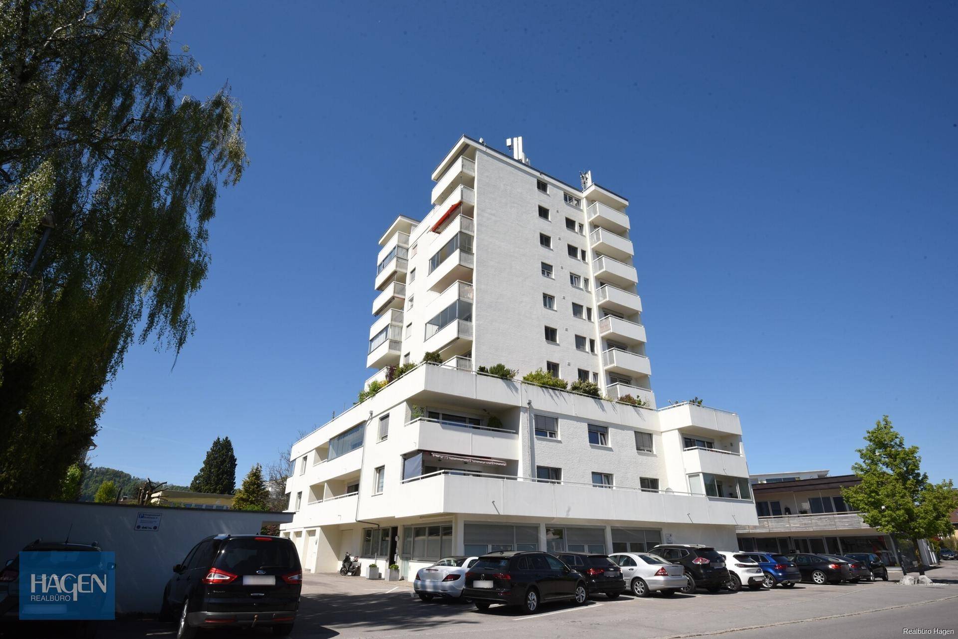 Modernes Mehrfamilienhaus mit mehreren Etagen, Balkonen und weißer Fassade.