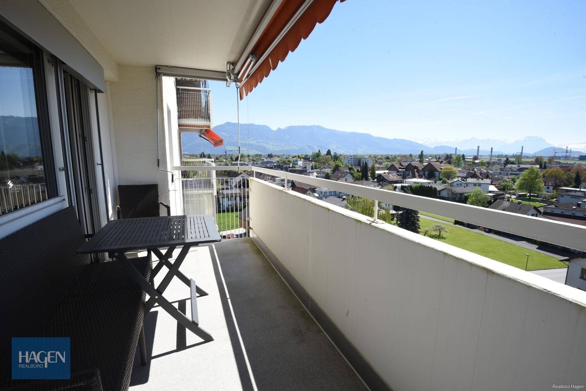 Langer Balkon mit Markise, Sitzgelegenheiten und weitem Blick auf die Berge.