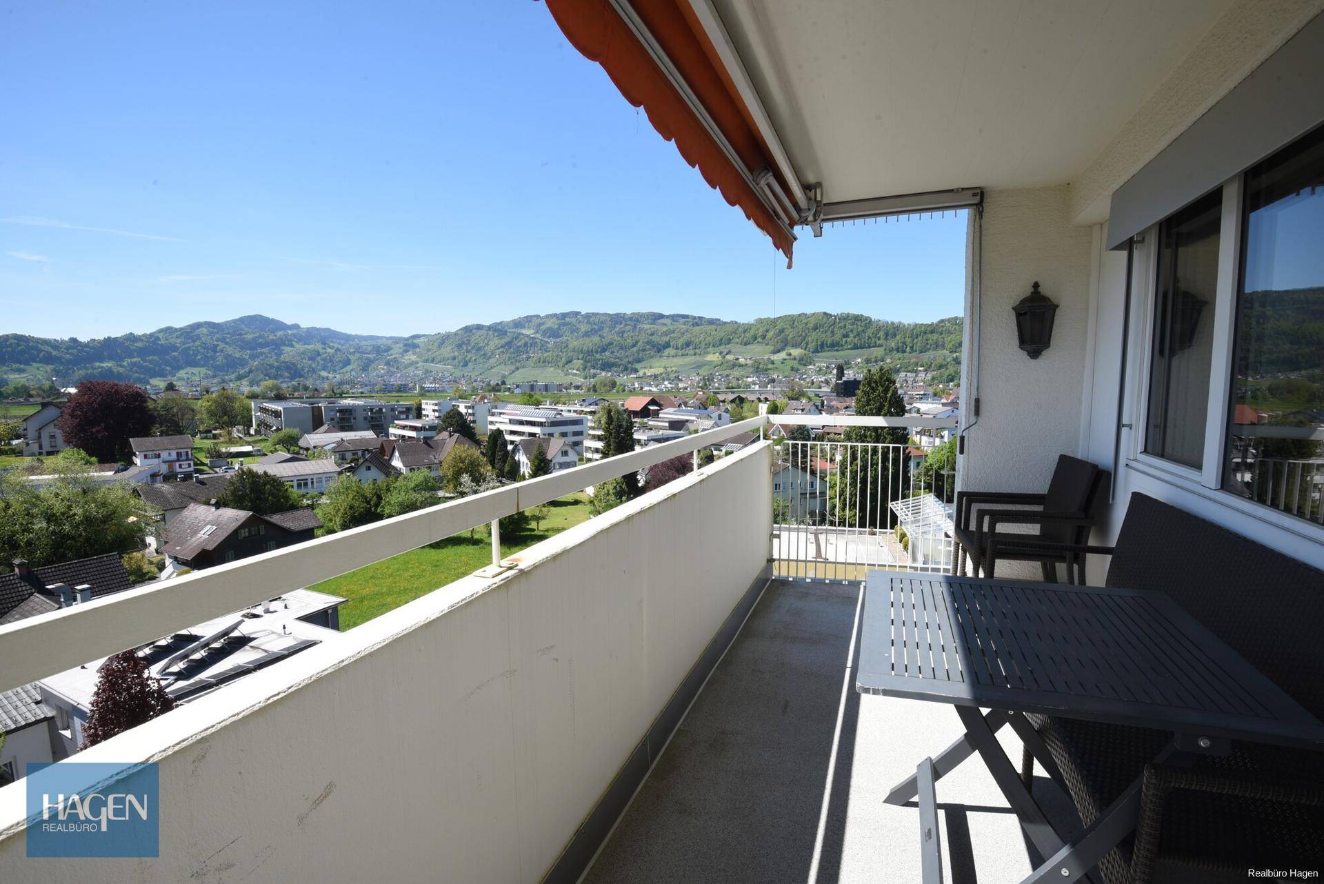 Sonniger Balkon mit Sitzgelegenheiten, Markise und schöner Aussicht auf die Umgebung.