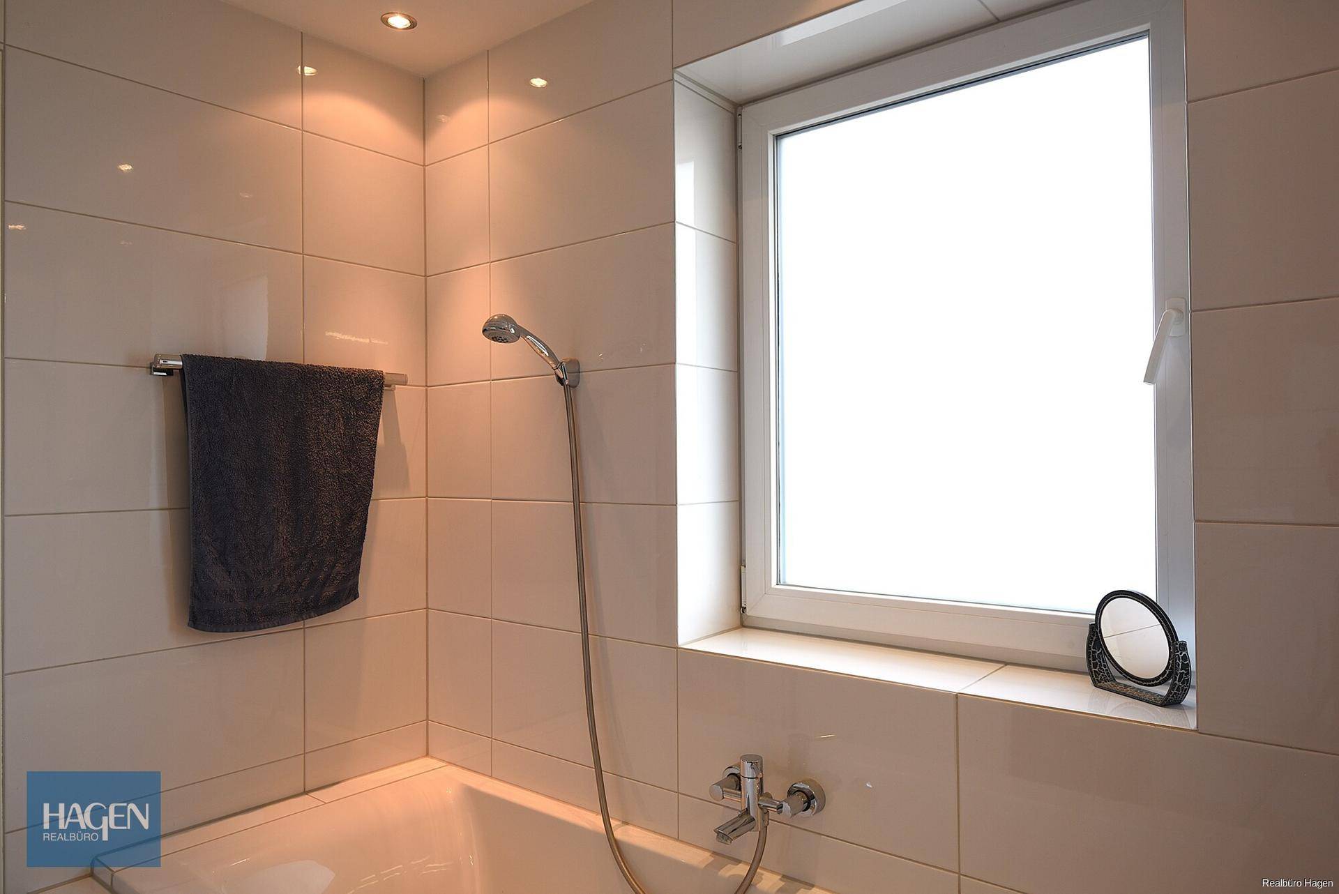 Helles Badezimmer mit Badewanne, Duschfunktion und einem Fenster für natürliche Belüftung.
