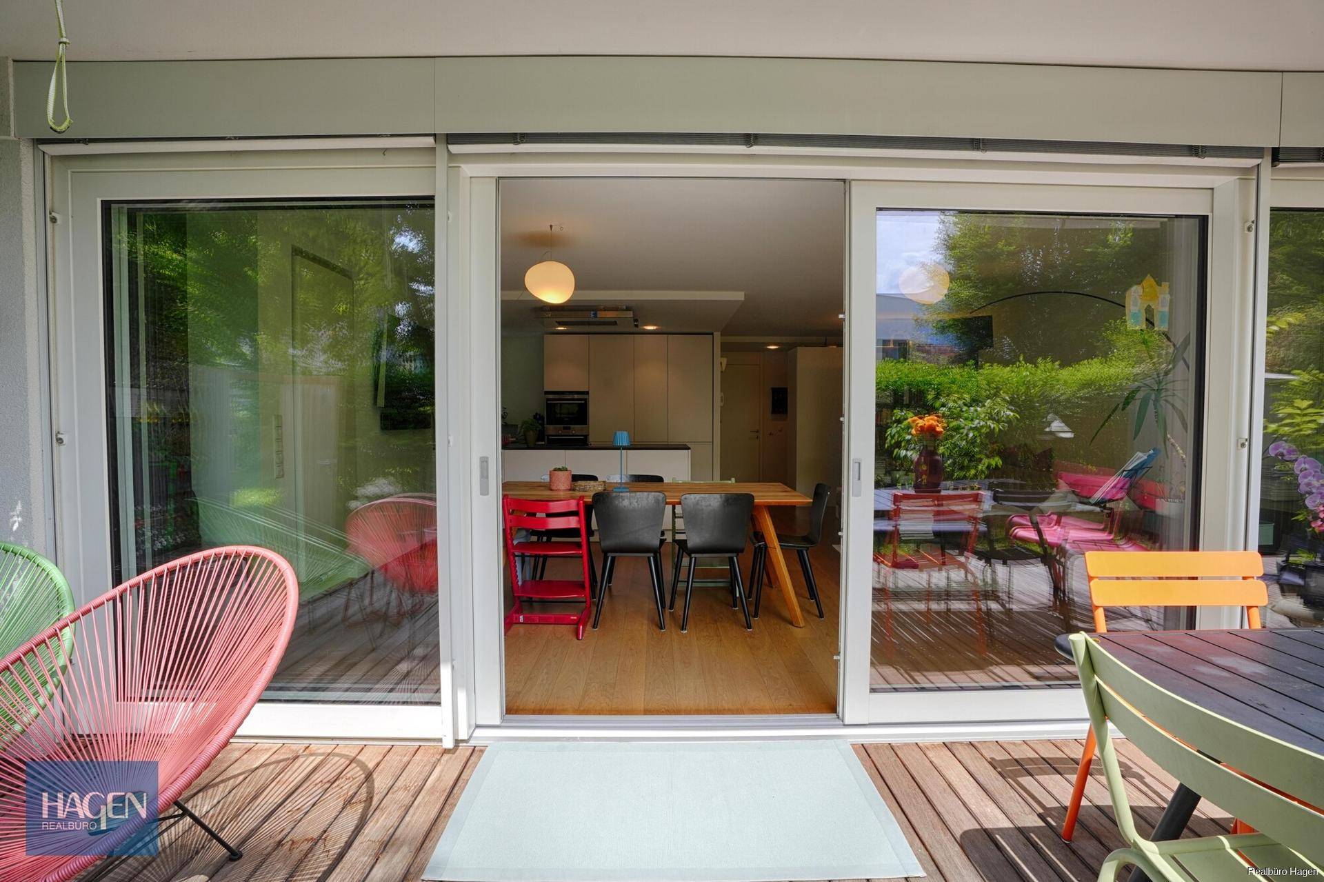 Blick von der Terrasse in den hellen, offenen Wohn-Essbereich mit moderner Küche.