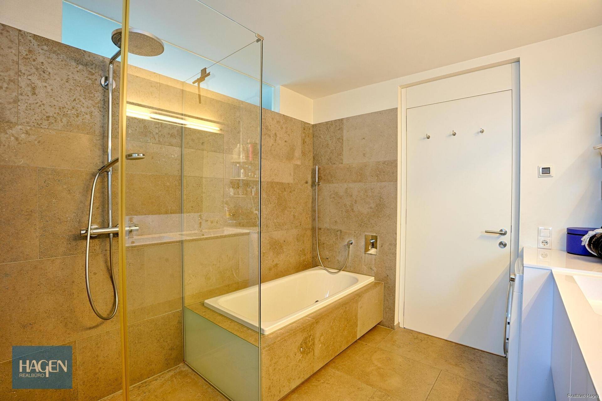 Modernes Badezimmer mit großer begehbarer Dusche und integrierter Badewanne, hell gefliest.