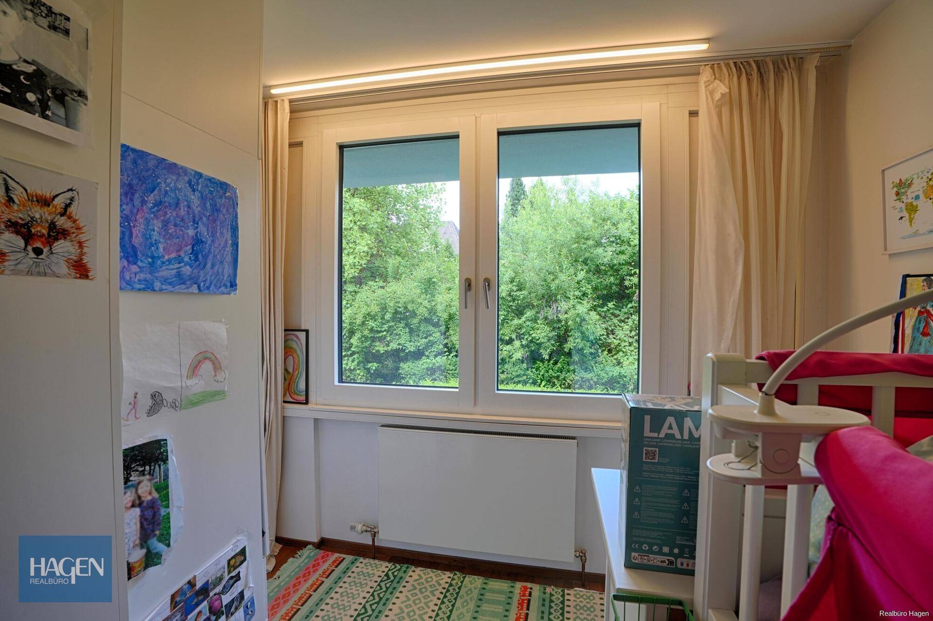 Kinderzimmer mit großem Fenster und Blick ins Grüne, hell und freundlich gestaltet.