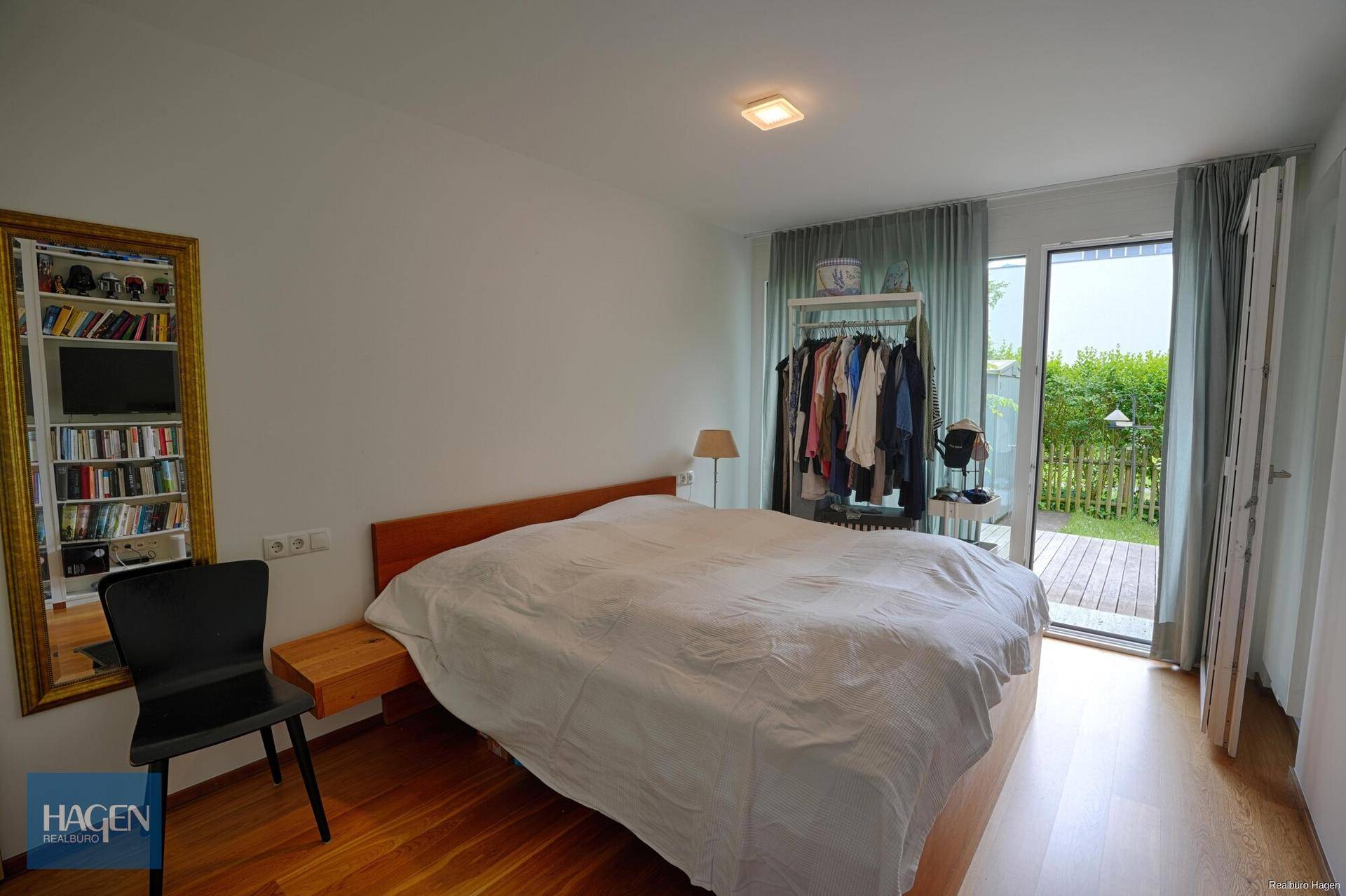 Helles Schlafzimmer mit Holzboden, direktem Zugang zum Garten und viel natürlichem Licht.