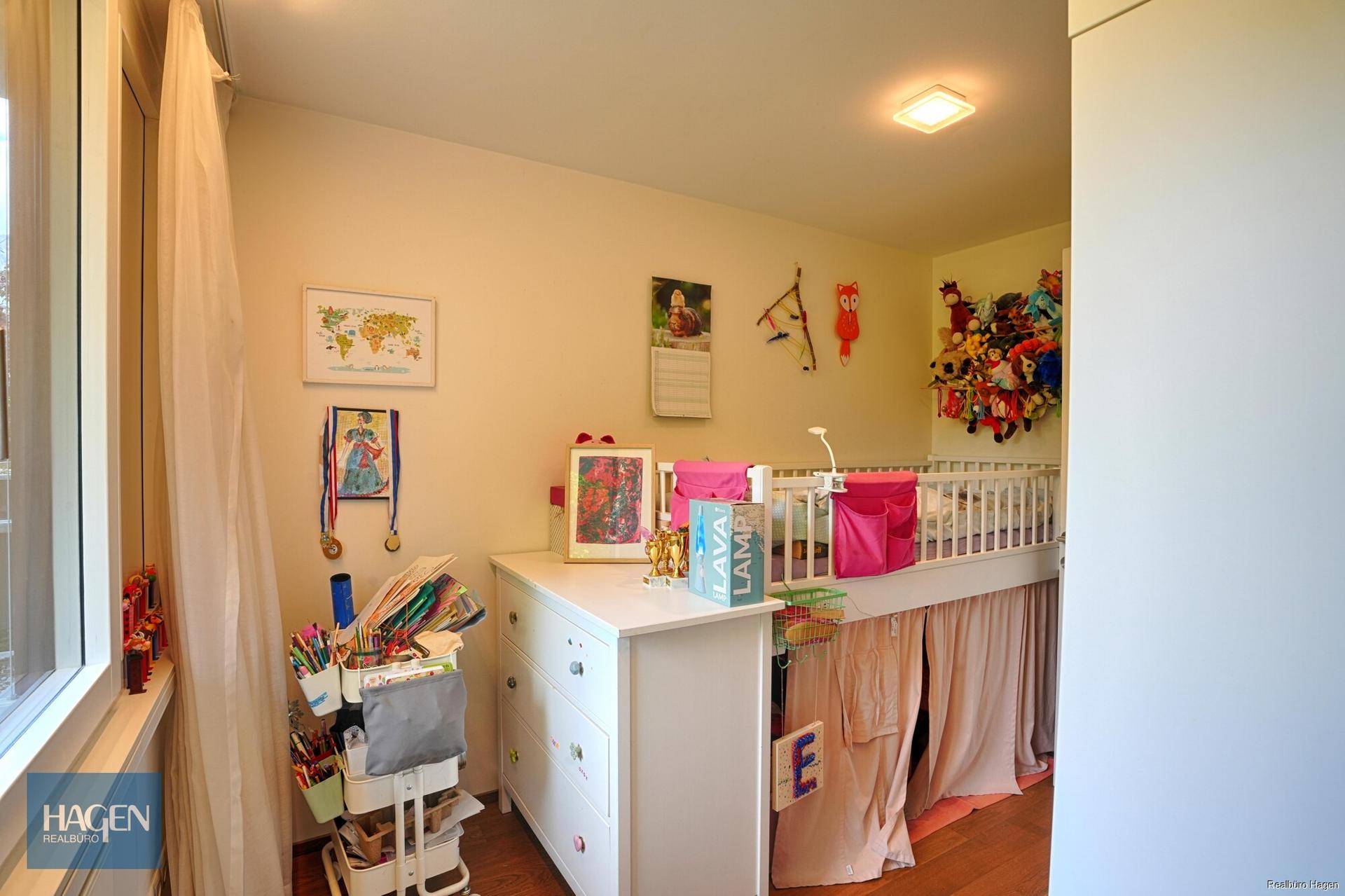 Gemütliches Kinderzimmer mit Babybett, Kommode und farbenfroher Dekoration.