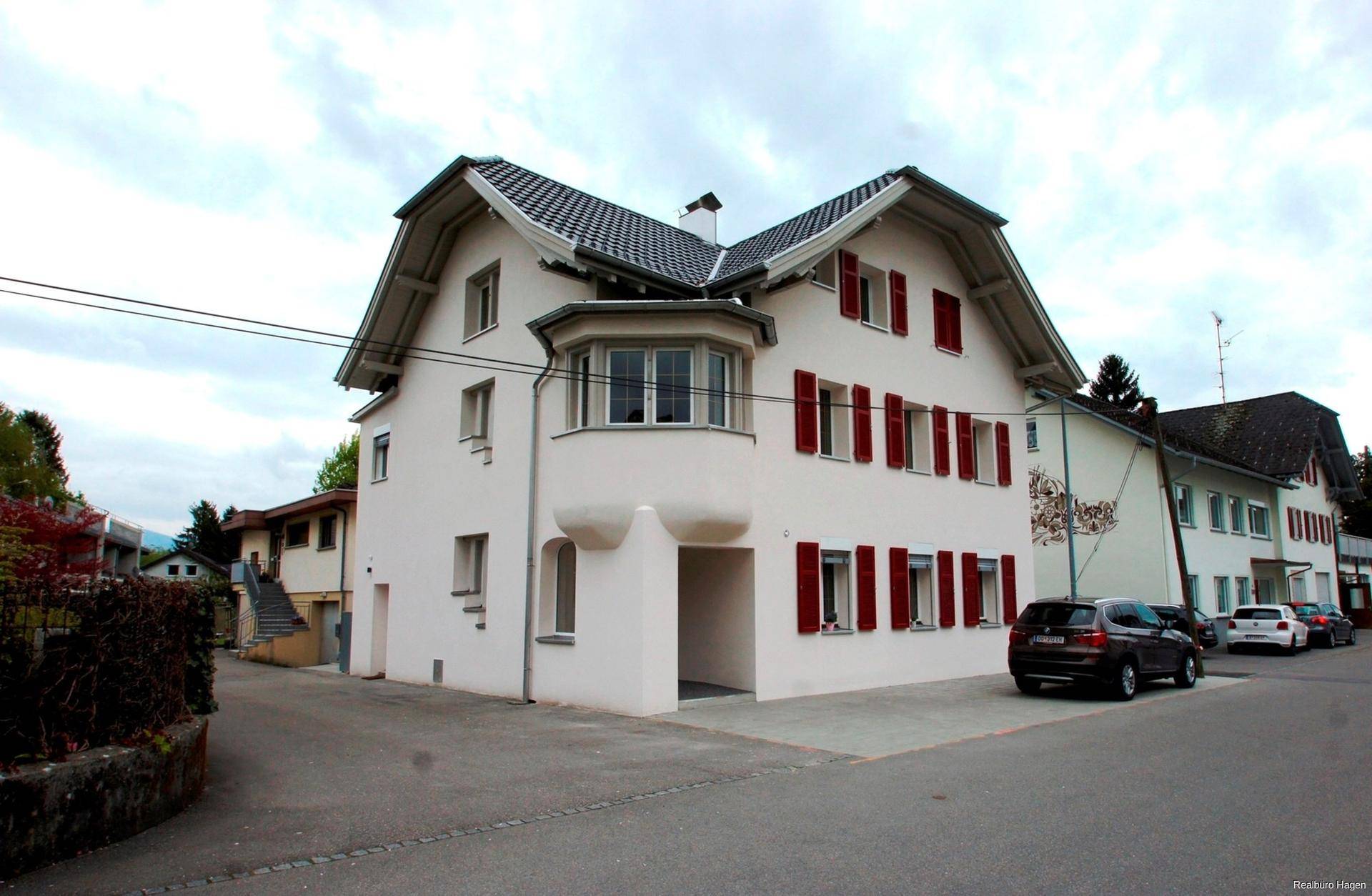 Charmantes Wohnhaus mit weißer Fassade, roten Fensterläden und traditioneller Architektur.
