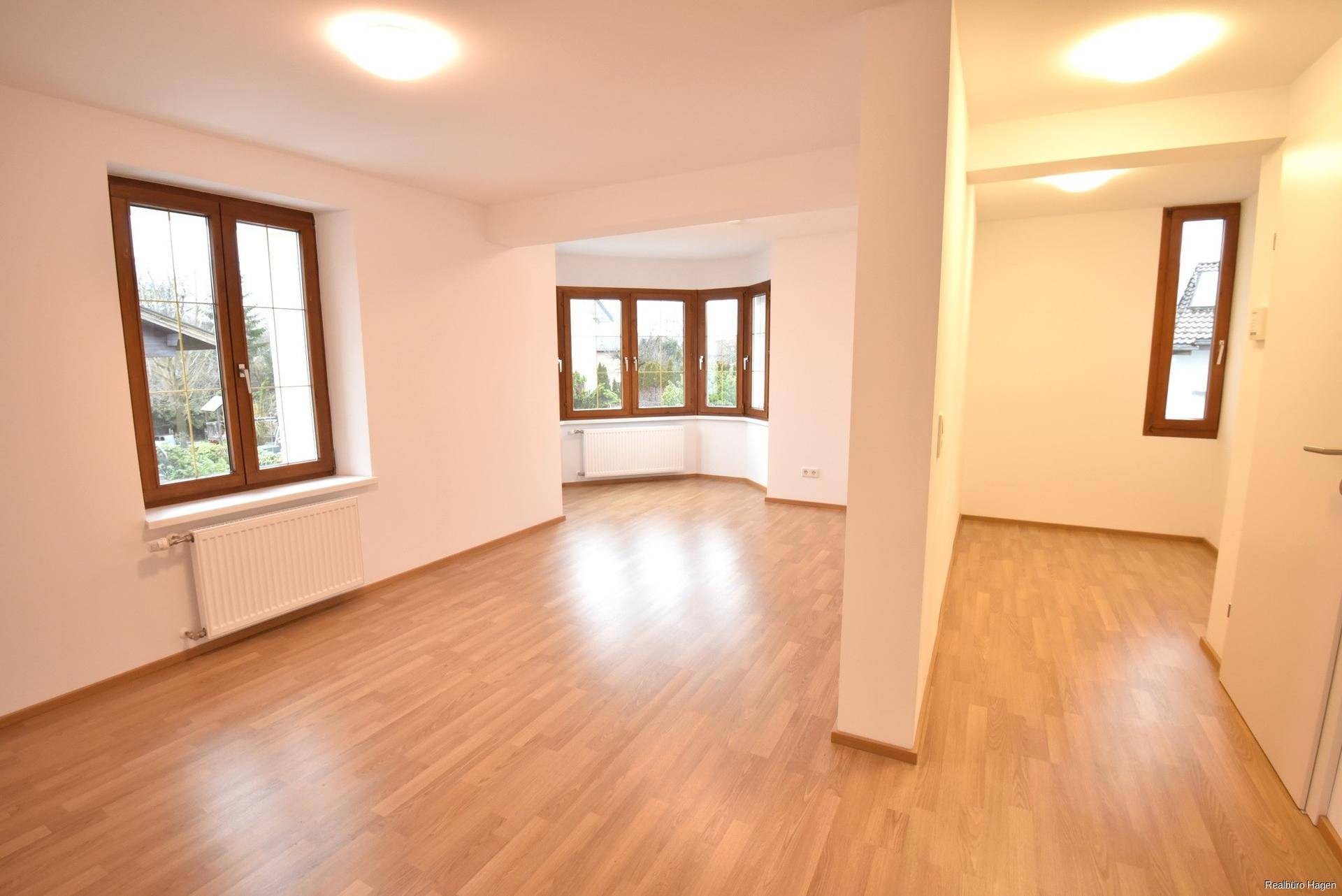 Heller Wohnraum mit Erkerfenstern und Laminatboden, der eine freundliche Atmosphäre schafft.