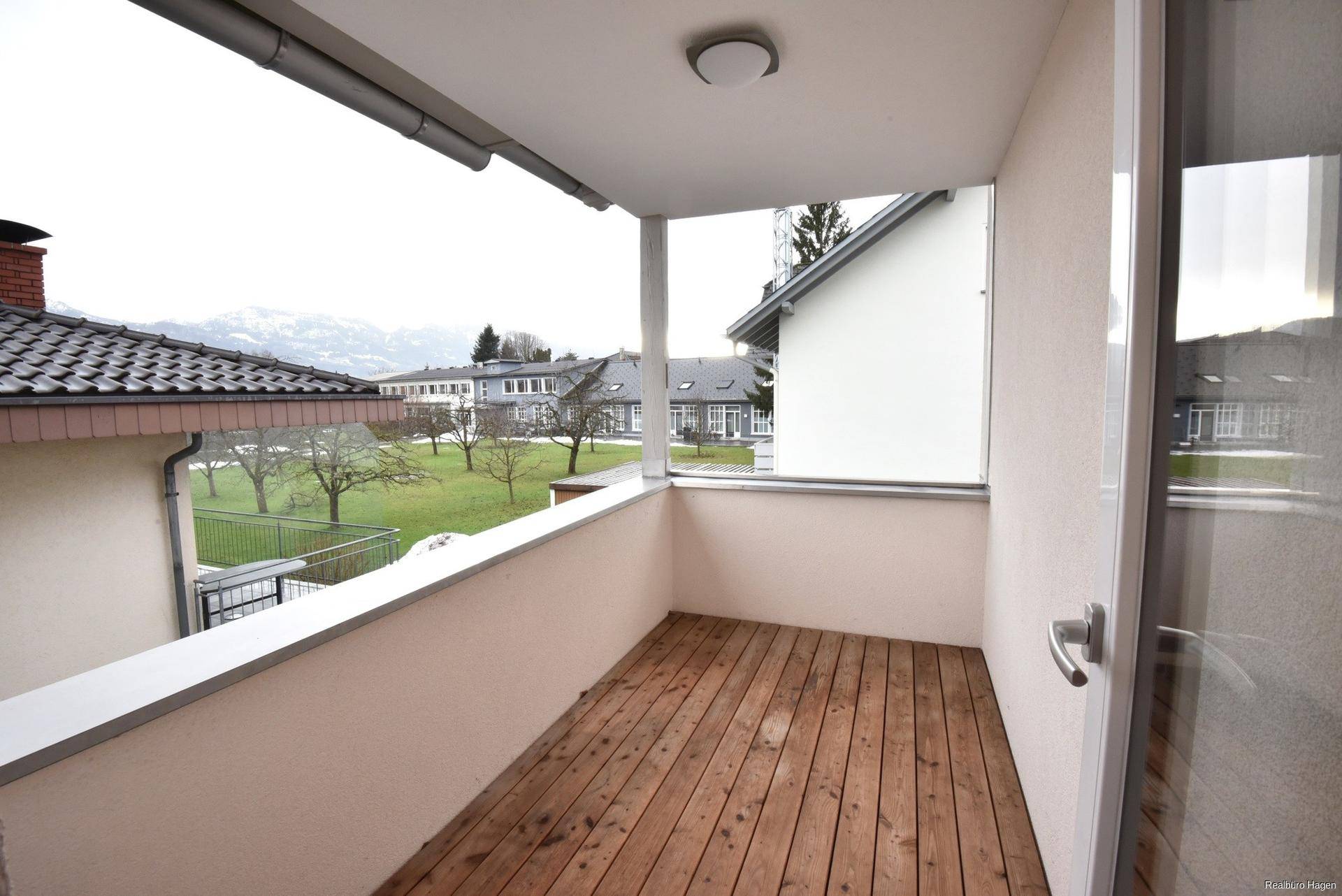 Gemütlicher Balkon mit Holzboden und Blick ins Grüne sowie auf die umliegende Landschaft.