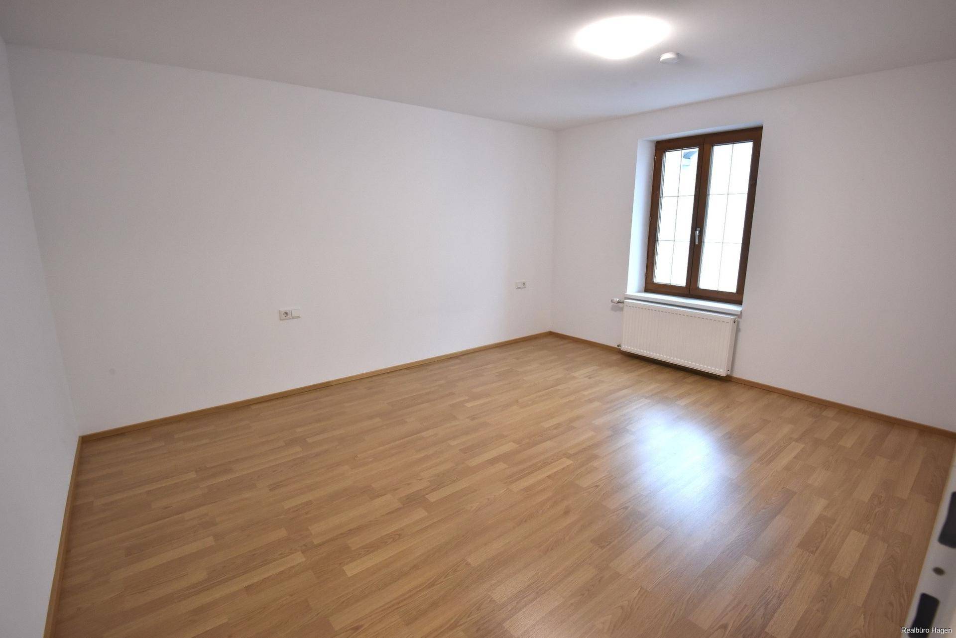 Ruhiges Schlafzimmer mit Laminatboden und einem Fenster, das ausreichend Tageslicht bietet.