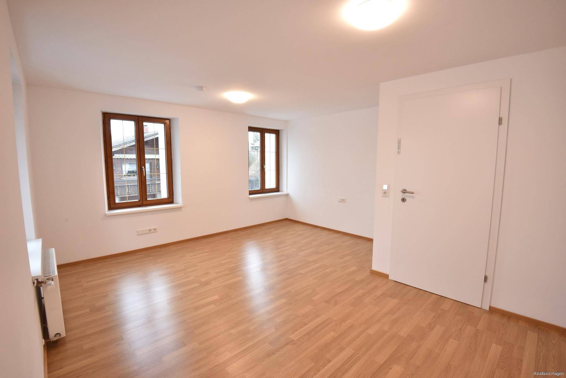 Helles Zimmer mit Laminatboden und zwei Fenstern, ideal als Wohn- oder Schlafzimmer nutzbar.