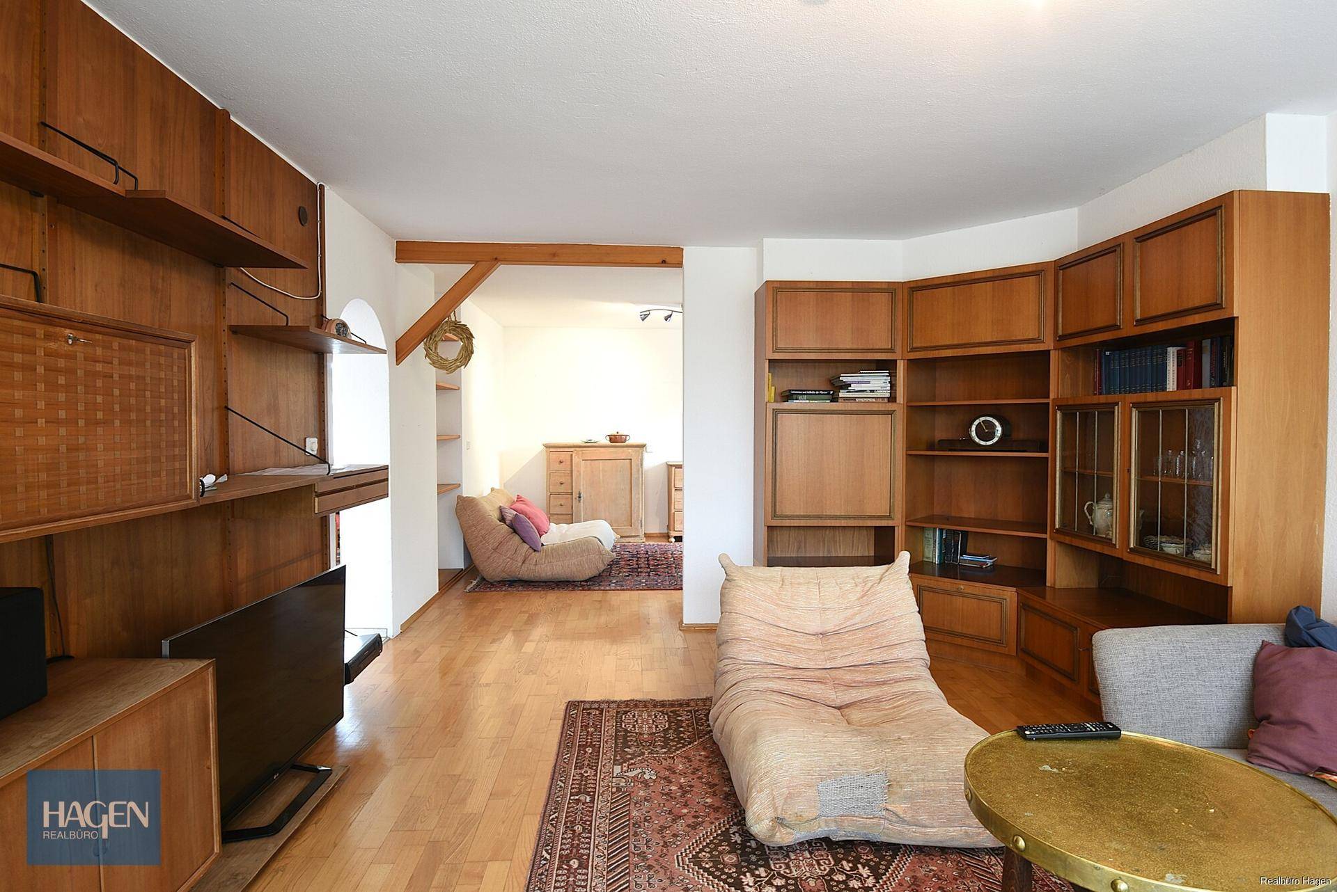 Gemütliches Wohnzimmer mit Holzmöbeln, Parkettboden und einem bequemen Sessel.