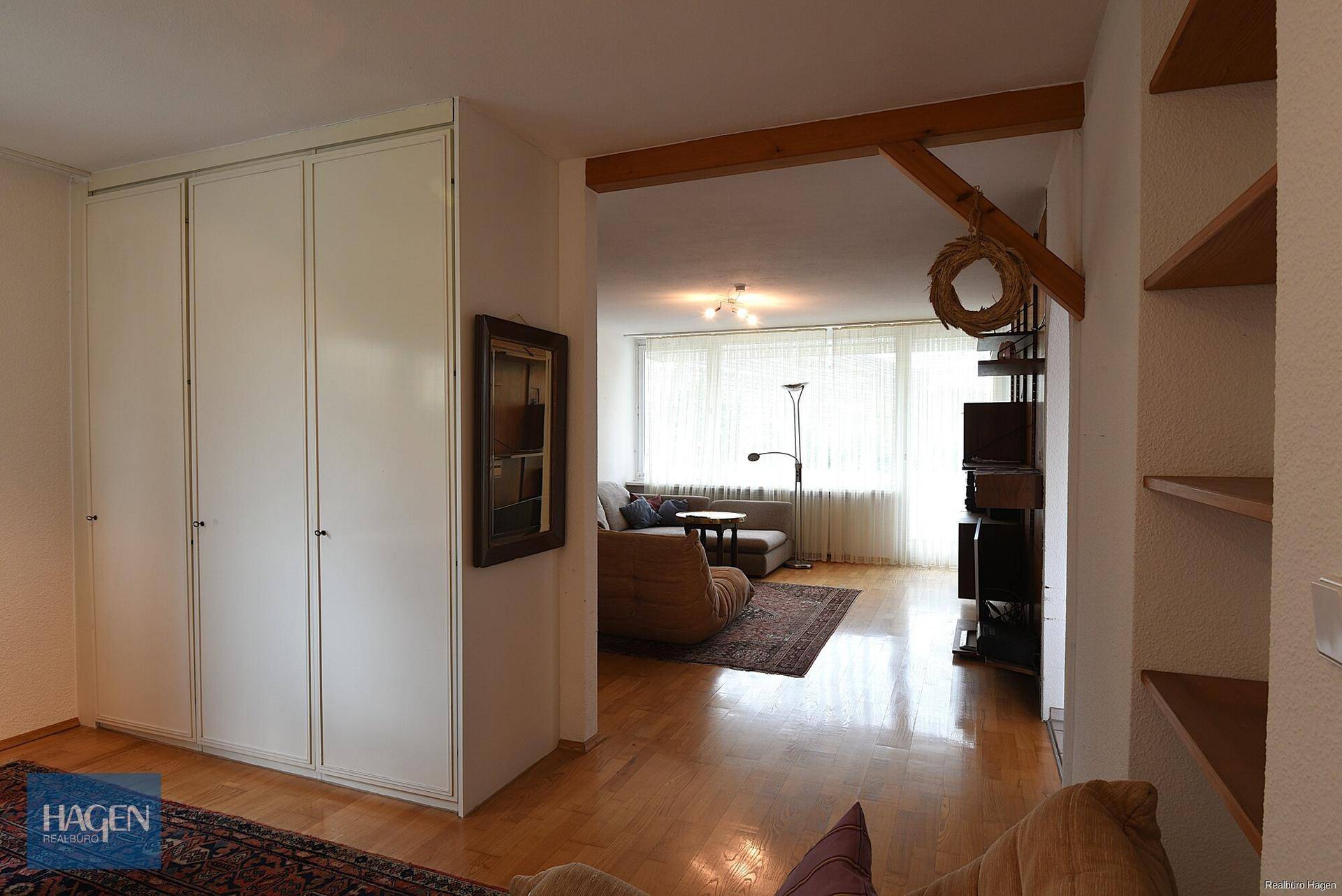 Heller Flur mit Einbauschränken und Blick in das angrenzende Wohnzimmer.