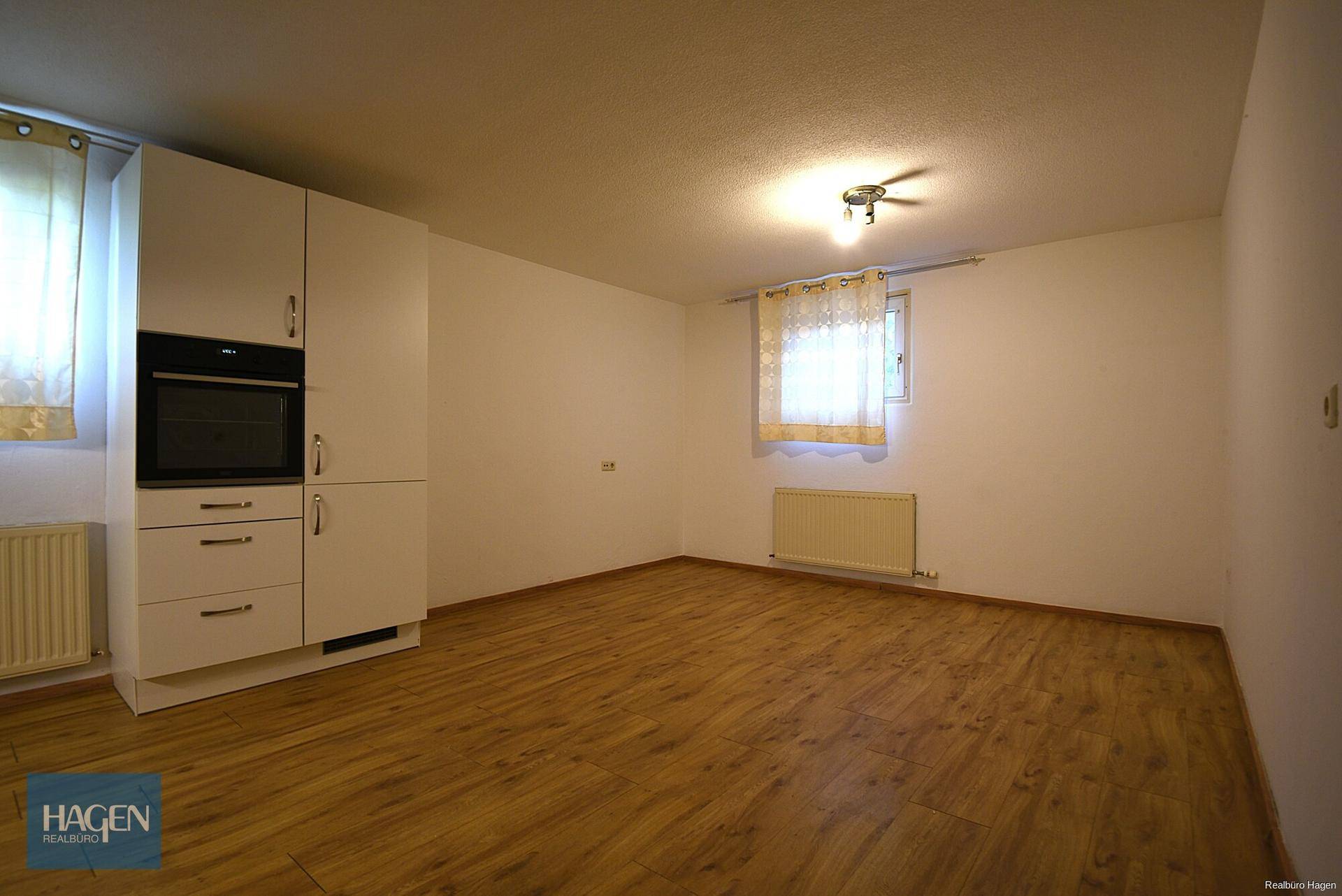 Leerer Raum mit Laminatboden, Heizkörper und Fenster, bereit zur individuellen Gestaltung.