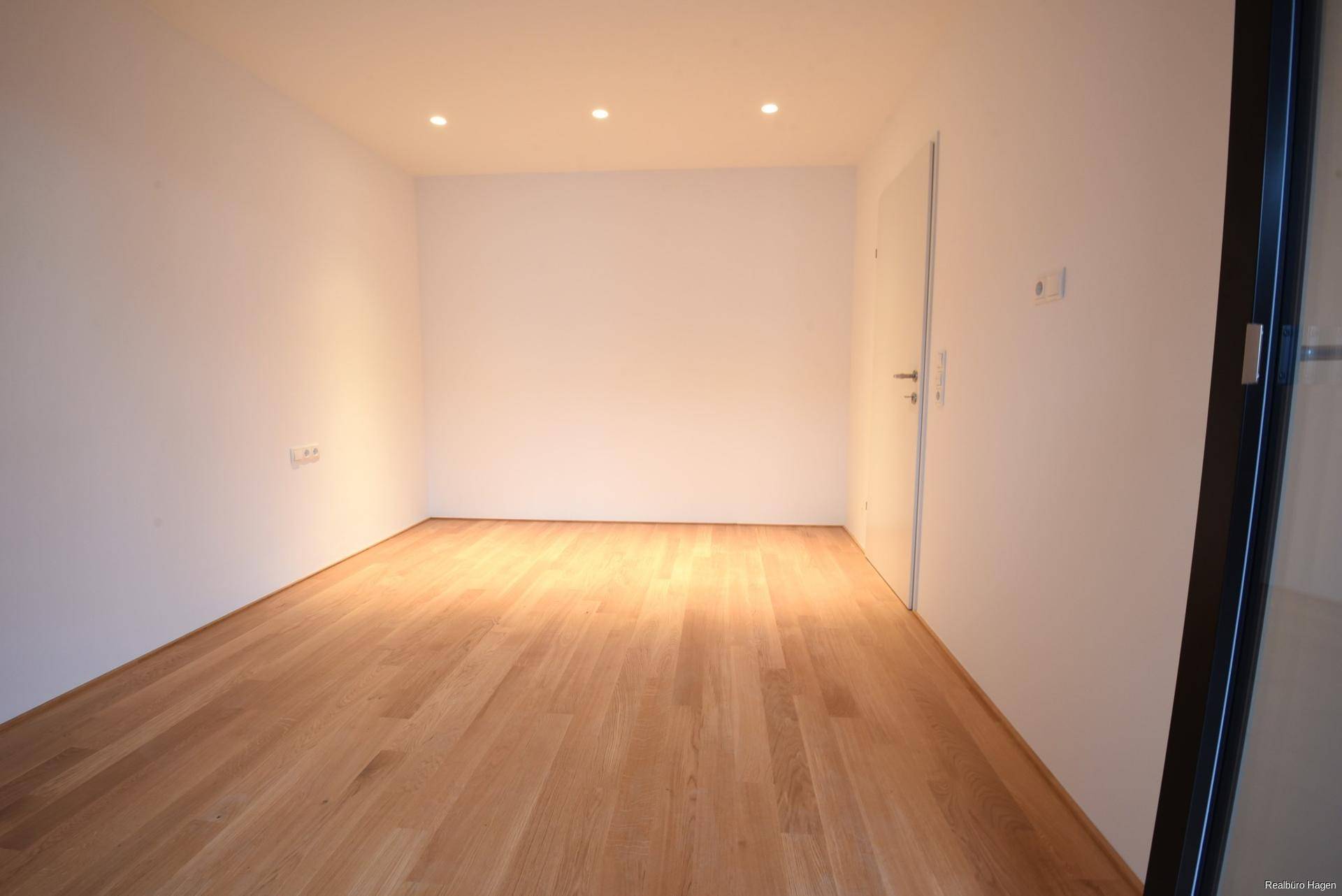 Heller Raum mit Parkettboden und Einbaustrahlern an der Decke.