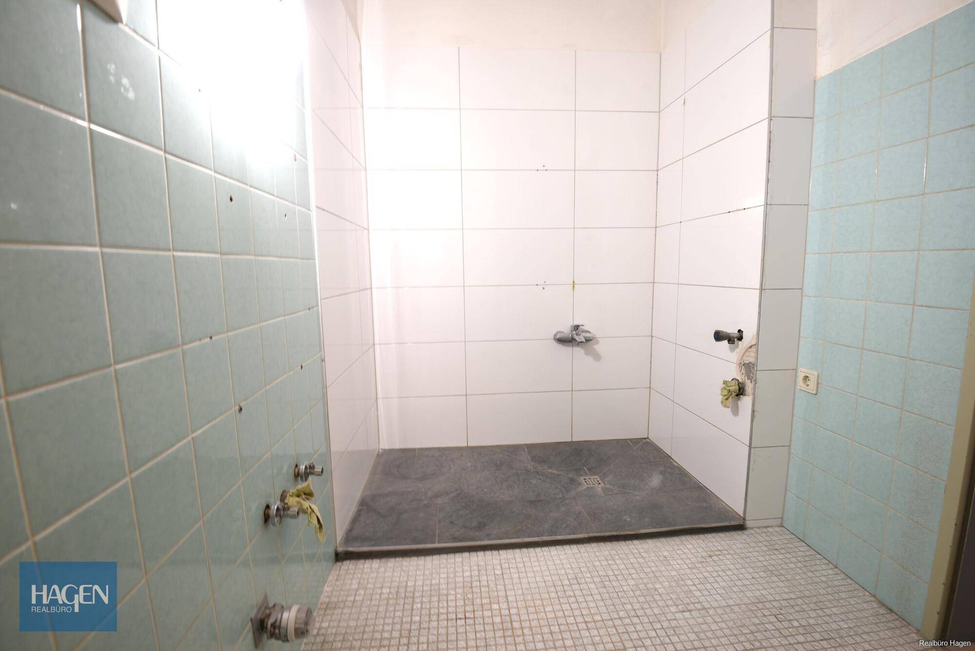 Duschbereich im Badezimmer mit weißen und grünen Fliesen, bietet Potenzial für eine Neugestaltung.