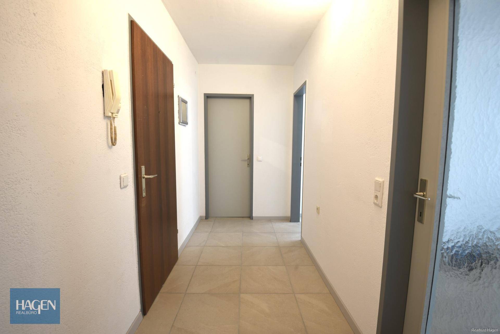 Geräumiger Flur mit hellen Fliesen und mehreren Türen, der verschiedene Zimmer verbindet.