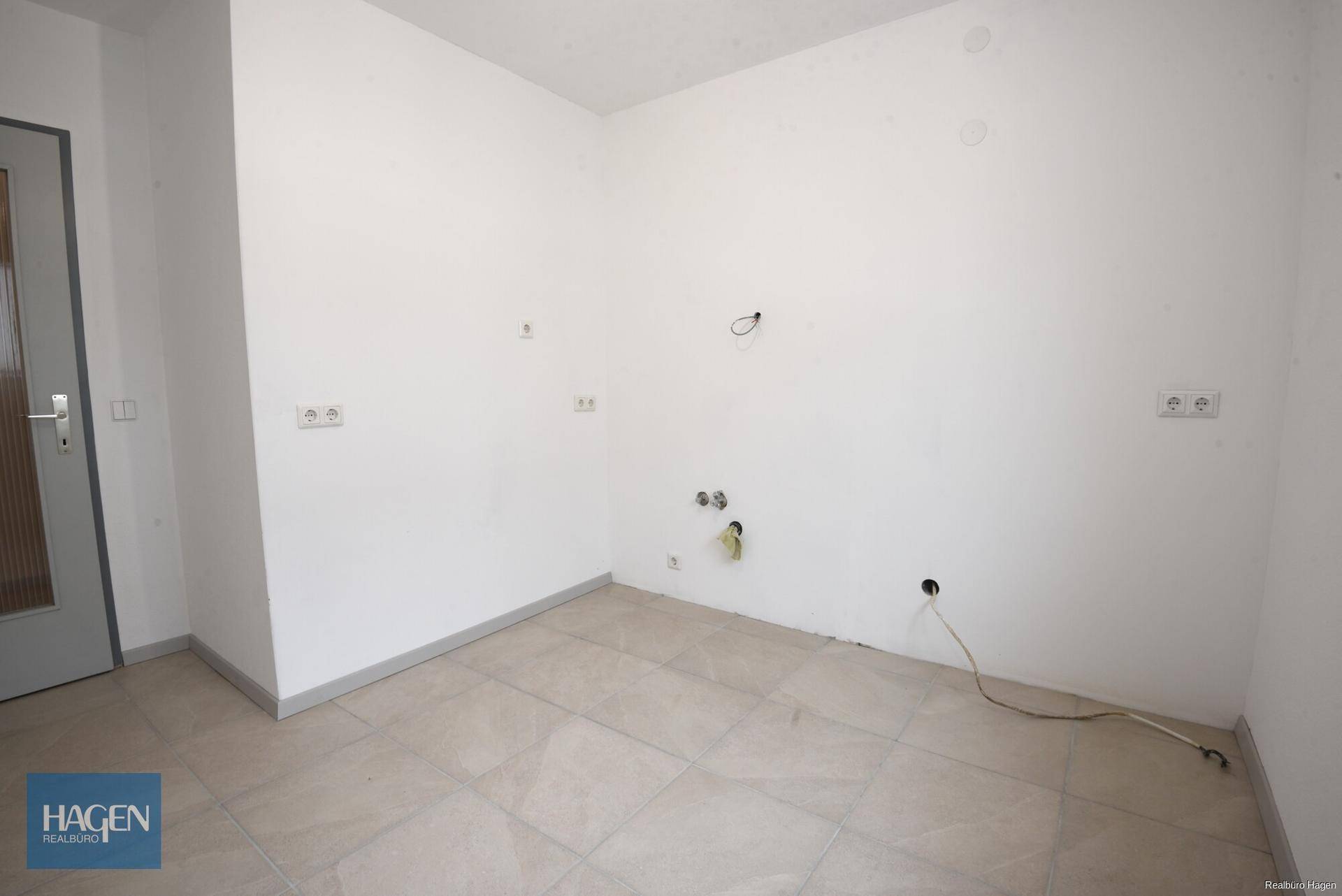 Heller Küchenraum mit Fliesenboden und allen notwendigen Anschlüssen für eine moderne Einbauküche.