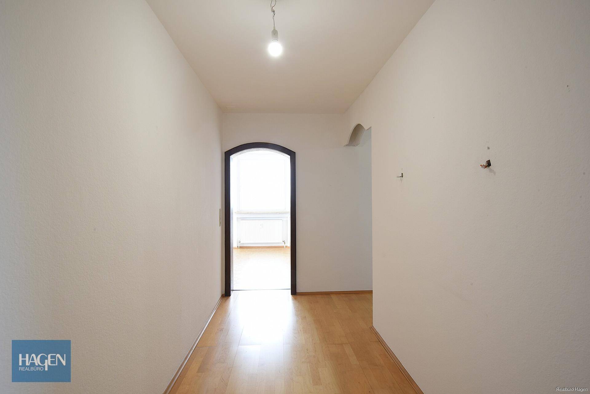 Langer, heller Flur mit Holzfußboden und Blick in einen weiteren Raum.