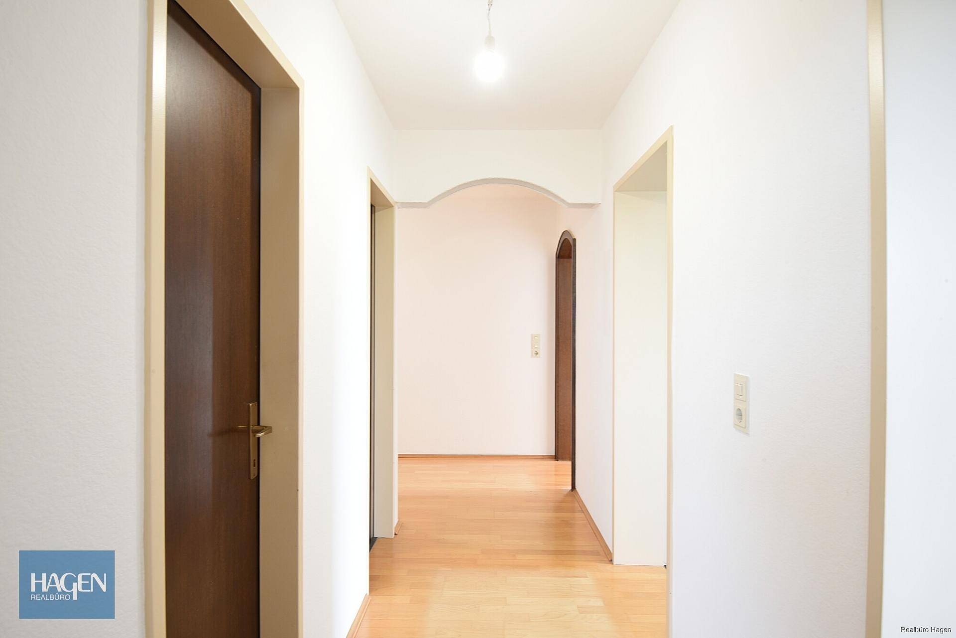 Heller Flur mit Holzfußboden und Zugang zu verschiedenen Räumen.