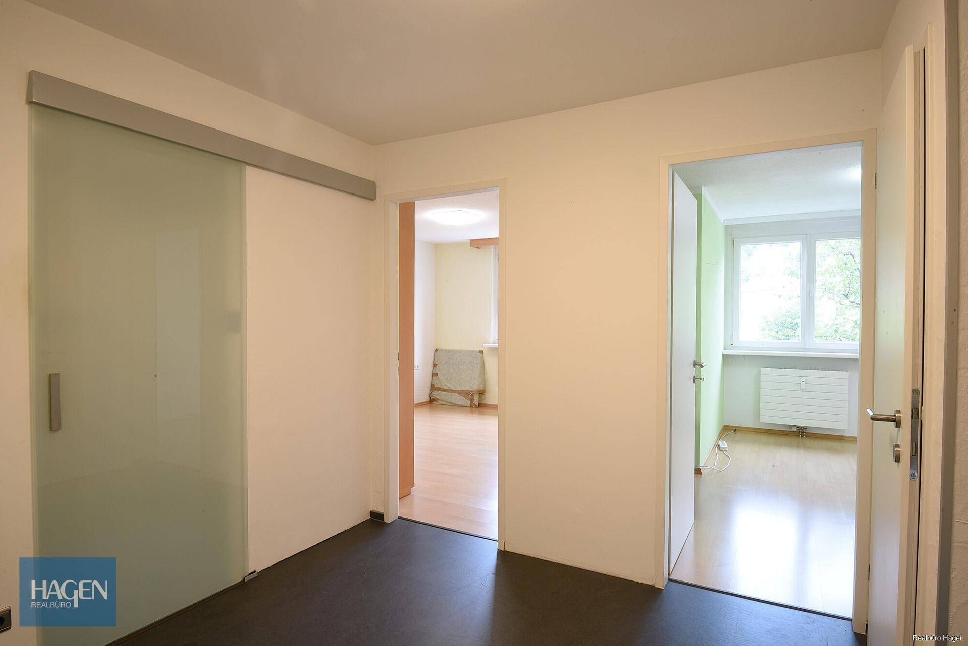 Heller Flur mit Schiebetür aus Glas und Zugang zu weiteren Zimmern.