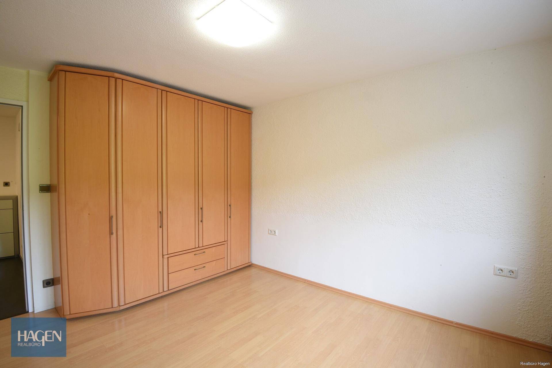 Geräumiges Schlafzimmer mit hellem Boden und großem Holzschrank.