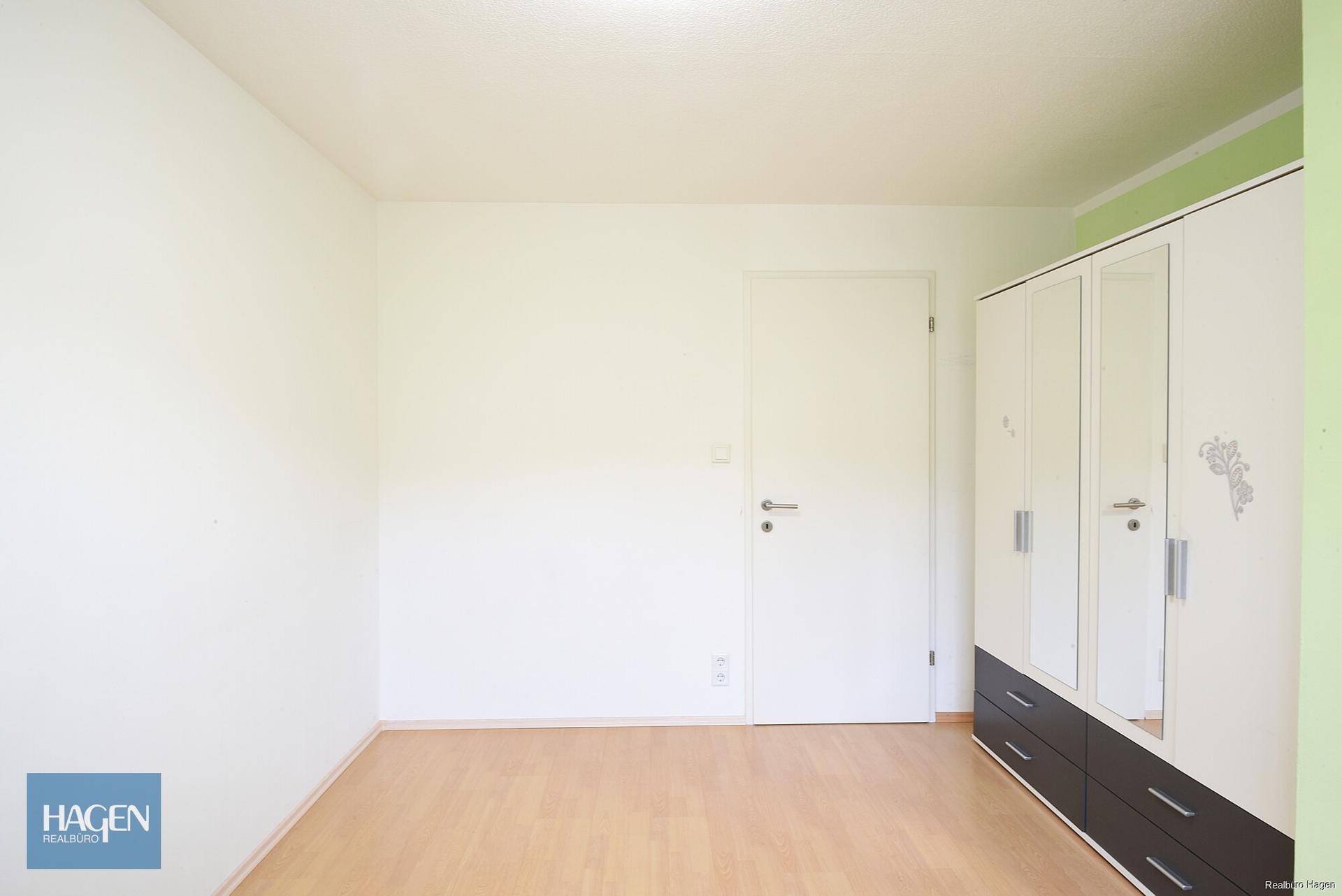 Schlafzimmer mit hellem Boden und modernem Kleiderschrank mit Spiegeltüren.